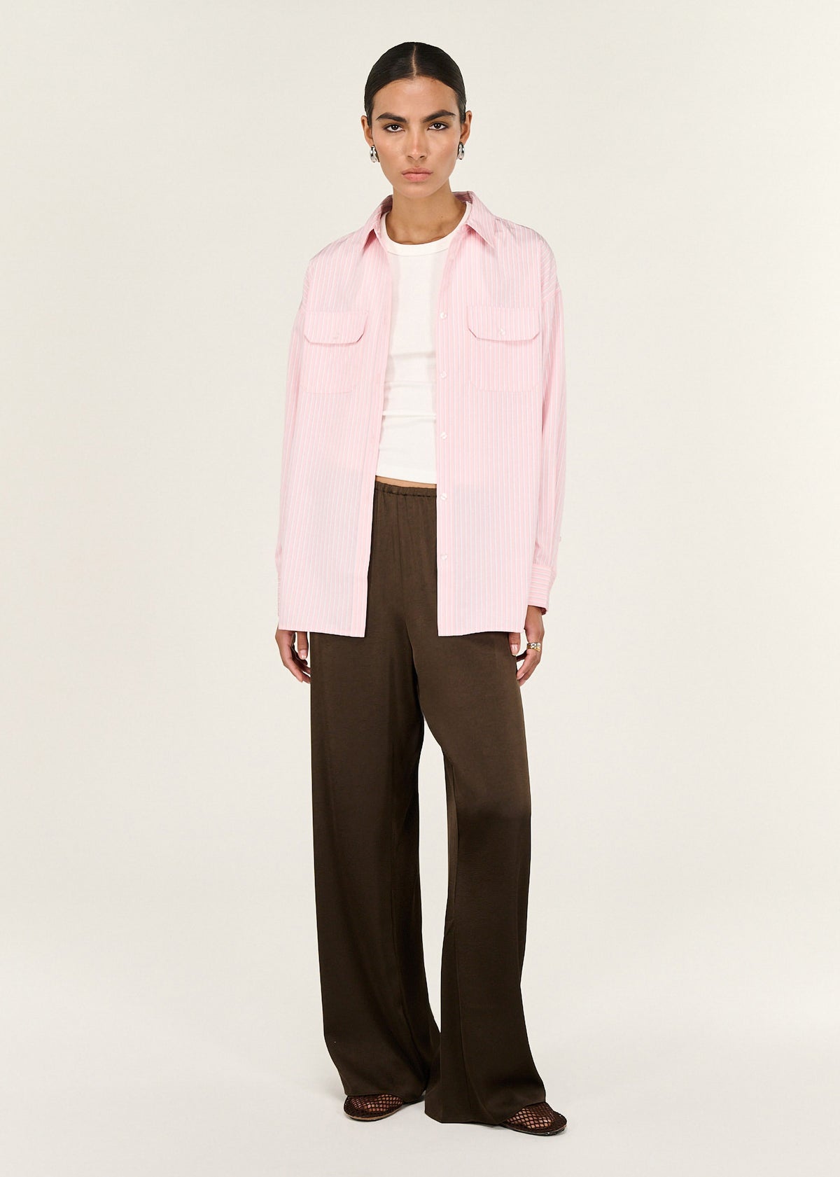 Model wearing Pink Pinstriped Shirt with a relaxed, longline silhouette and dual front patch pockets.