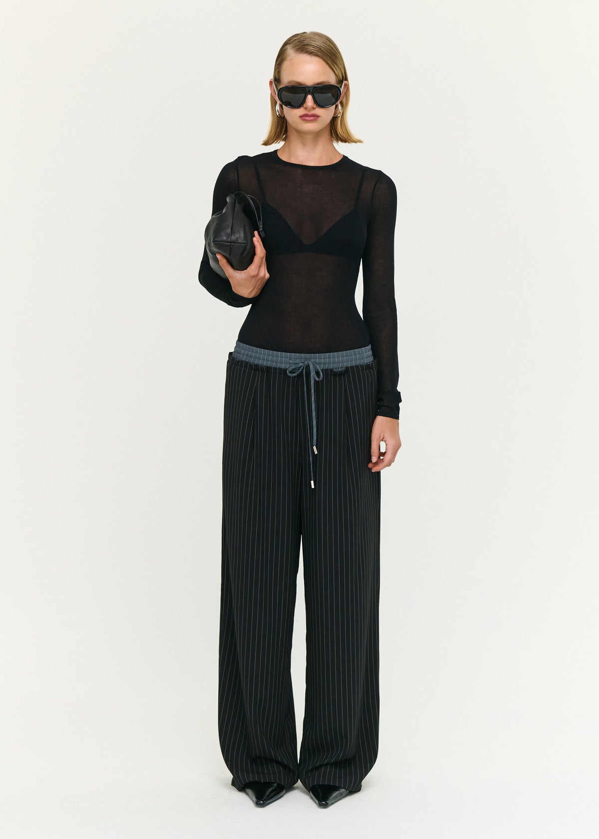 Model wearing Pinstripe Relaxed Drawstring Pants with a soft woven fabrication and a pinstripe design.