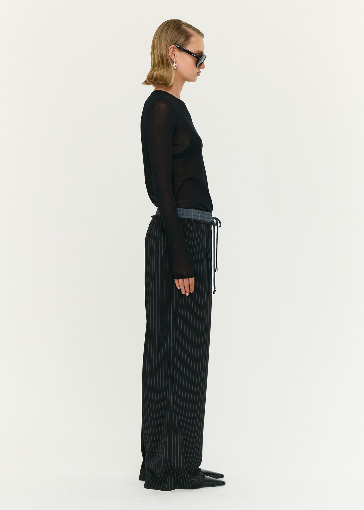 Side view of the Pinstripe Relaxed Drawstring Pants, showing side seam pockets and a full length fit.