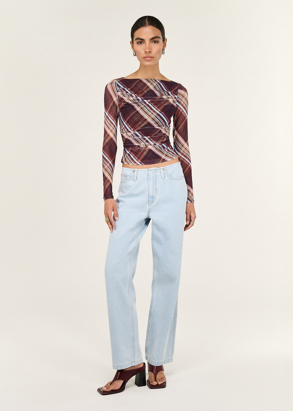 Model wearing Plaid Mesh Boat Neck Top with Gather Detail with a ruched detailing through bodice and an all-over diagonal plaid print.