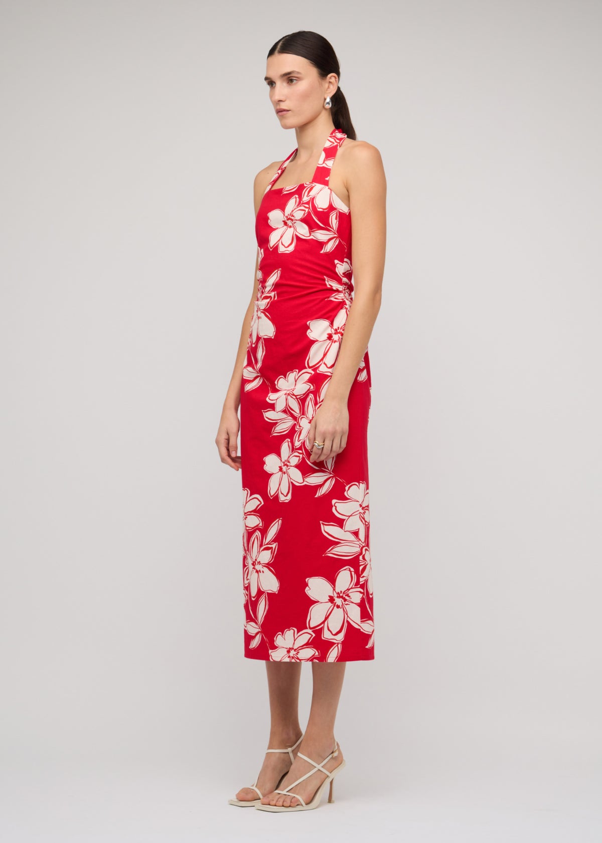 Model wearing Red and White Cotton Floral Halter-Neck Midi Dress with a red with white floral print, turned to the side.