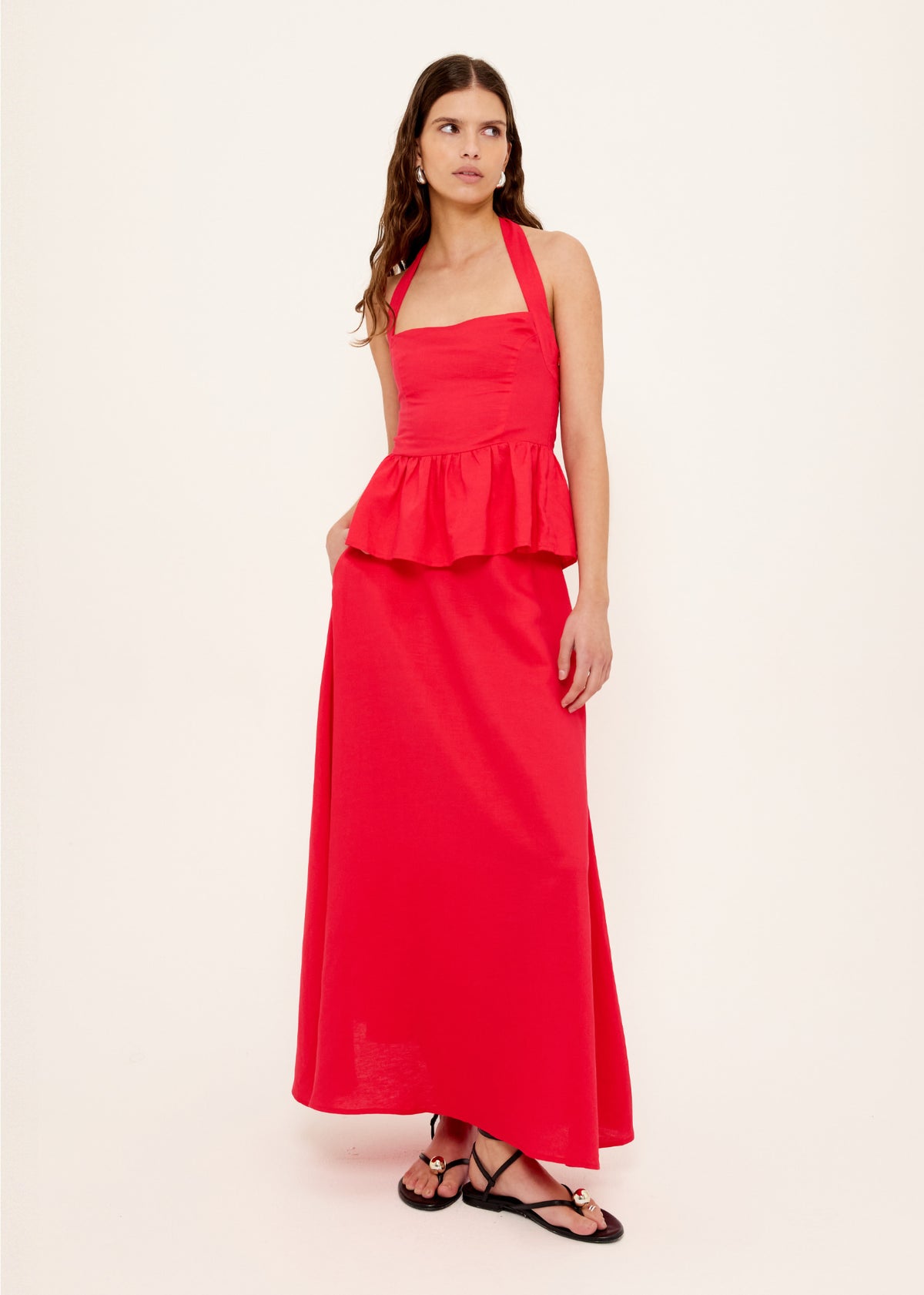 Model wearing Red Linen Blend Halter Peplum Top with a fitted bodice with ruched detailing and a peplum hem, turned to the side.