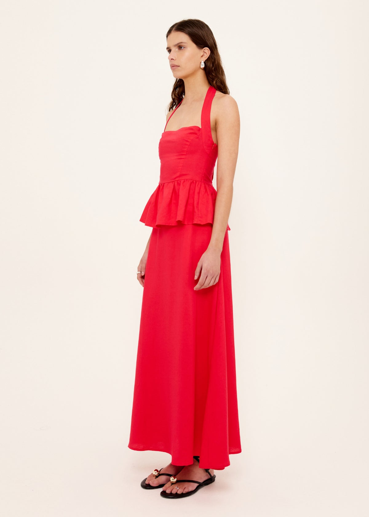 Angled view of the Red Linen Blend Halter Peplum Top with a halter neckline with tie back and a shirred back panel.