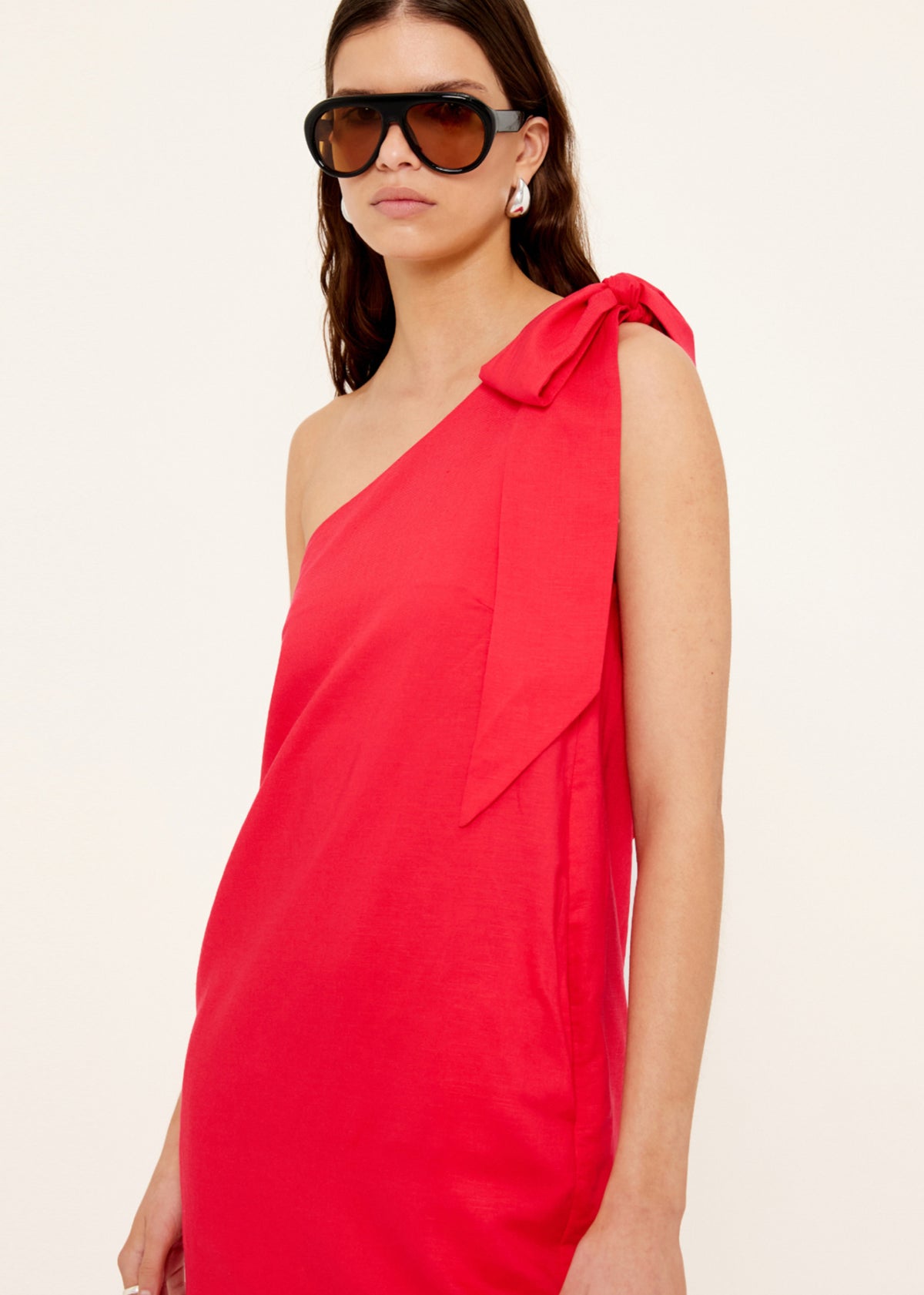 Close-up of the Red Linen Blend One Shoulder Mini Dress, showing a one-shoulder neckline and a statement self-tie bow detail.
