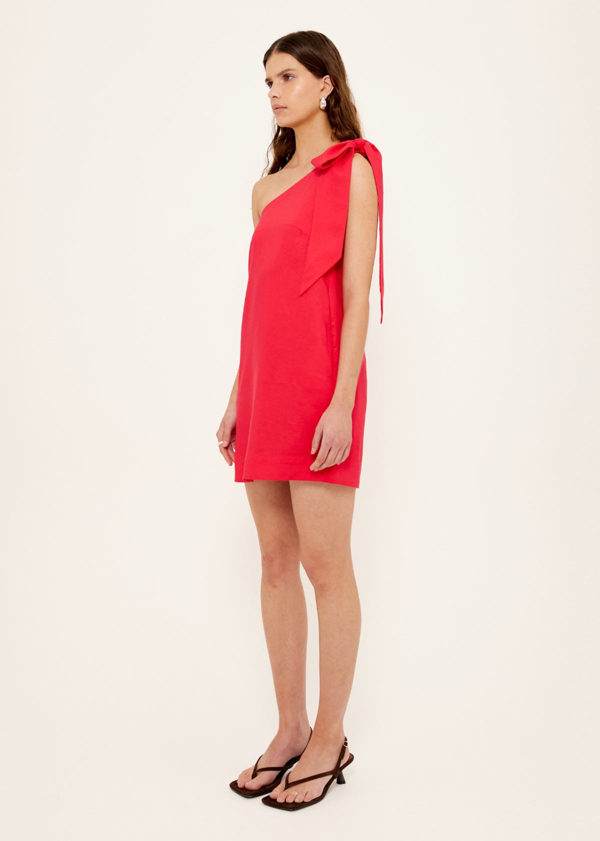 Side view of the Red Linen Blend One Shoulder Mini Dress, showing a one-shoulder neckline and a statement self-tie bow detail.