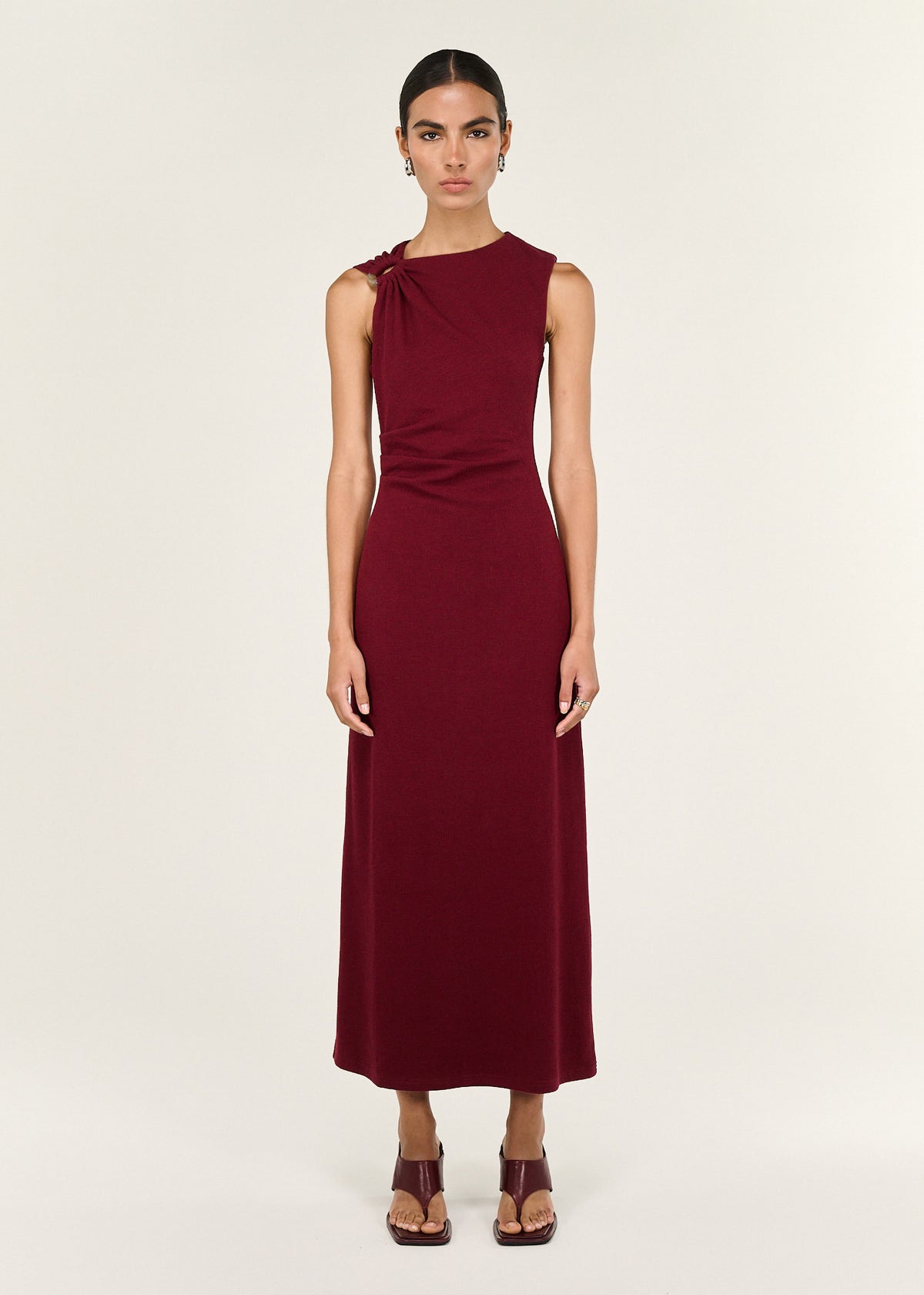 Model wearing Red Stretch Jersey Midi Dress, showing a sleeveless cut and a fitted waist with subtle drape.