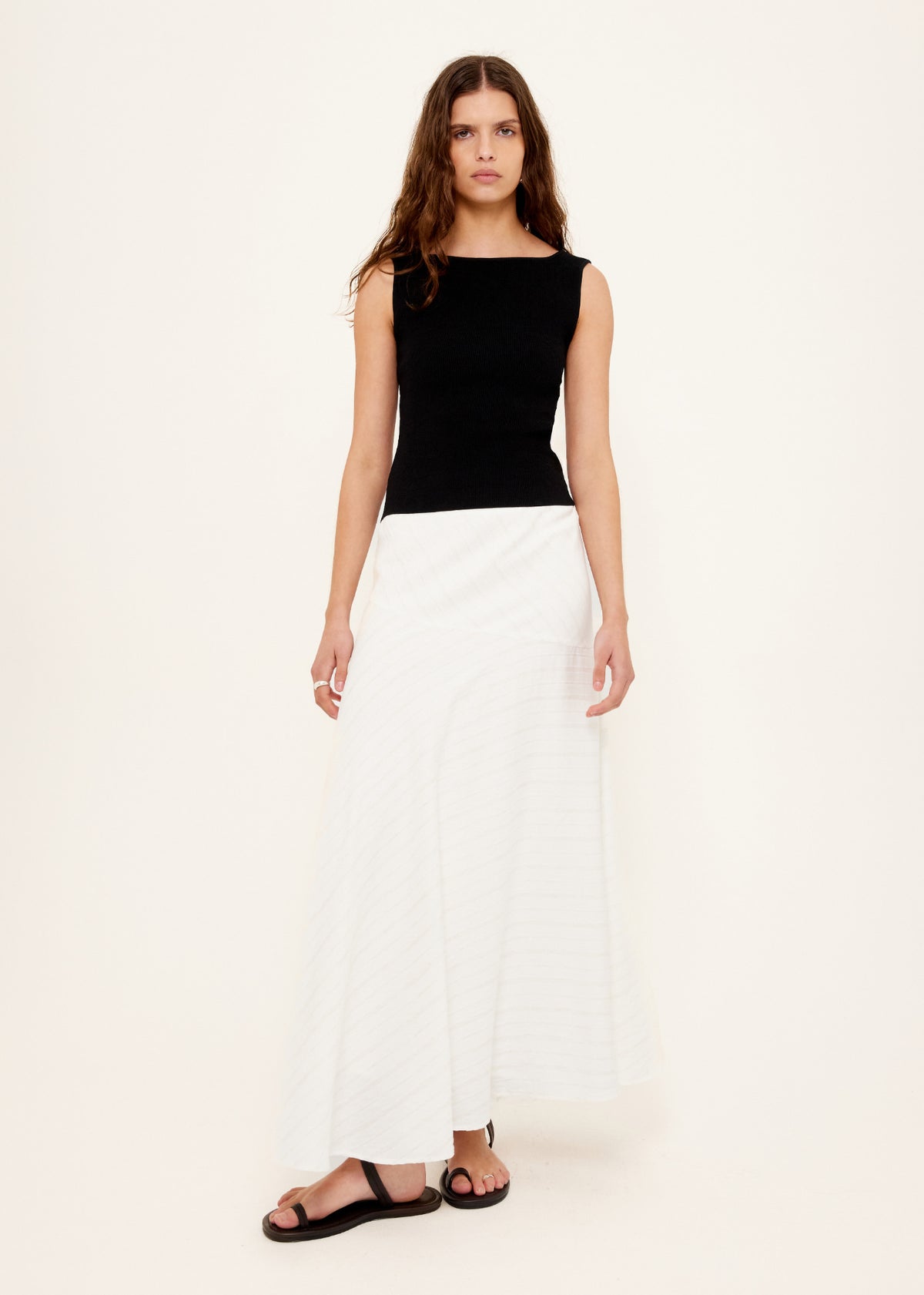 Model wearing Reversible Black Knit Tank Top with a reversible neckline - scoop or boat neck and a fitted silhouette, turned to the side.