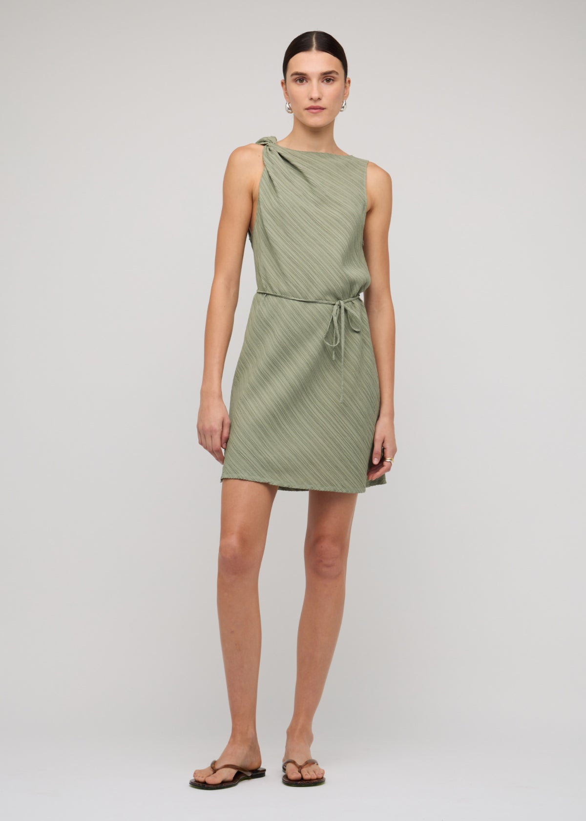 Model wearing Sage Green Mini Dress With Tie Waist with a sage green colour-way and a textured fabrication.