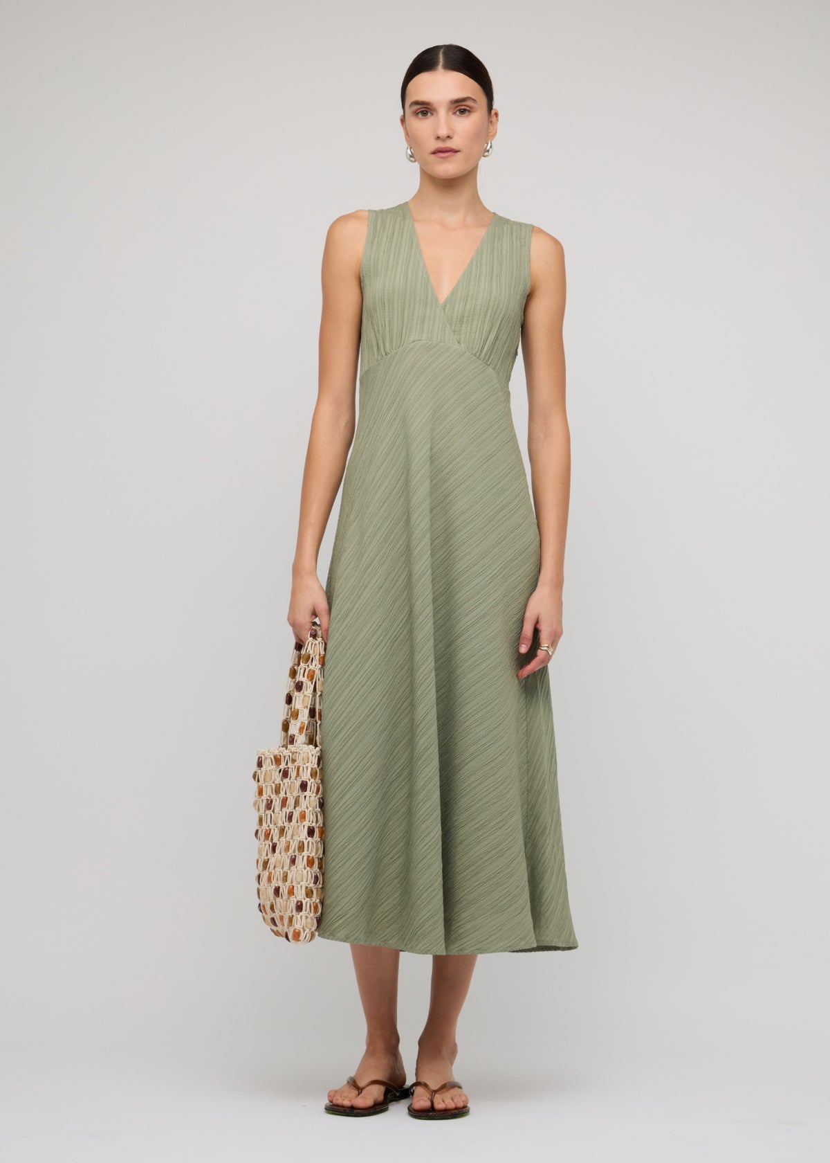 Model wearing Sage Green V-Neck Bias Midi Dress with a sleeveless cut and a bias-cut silhouette.