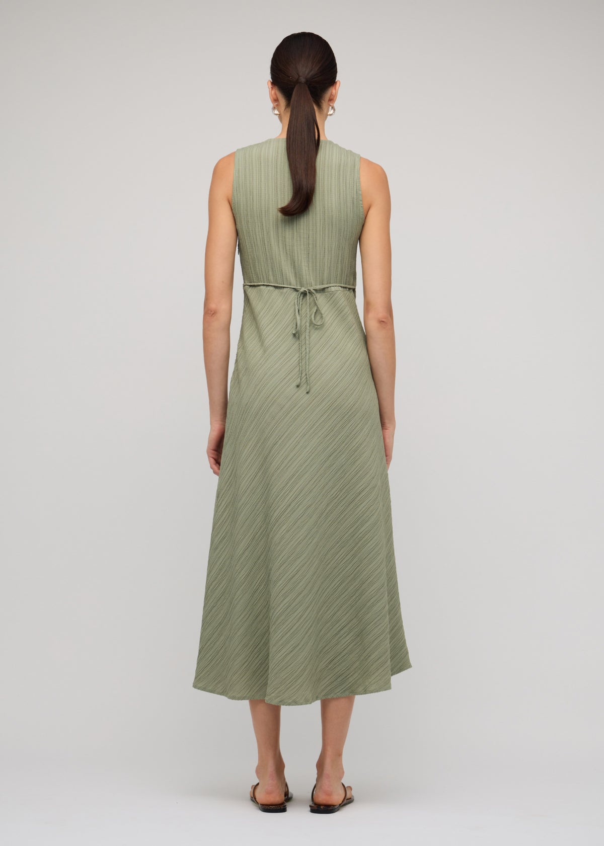 Back view of the Sage Green V-Neck Bias Midi Dress with an adjustable waist tie at the back and a sleeveless cut.
