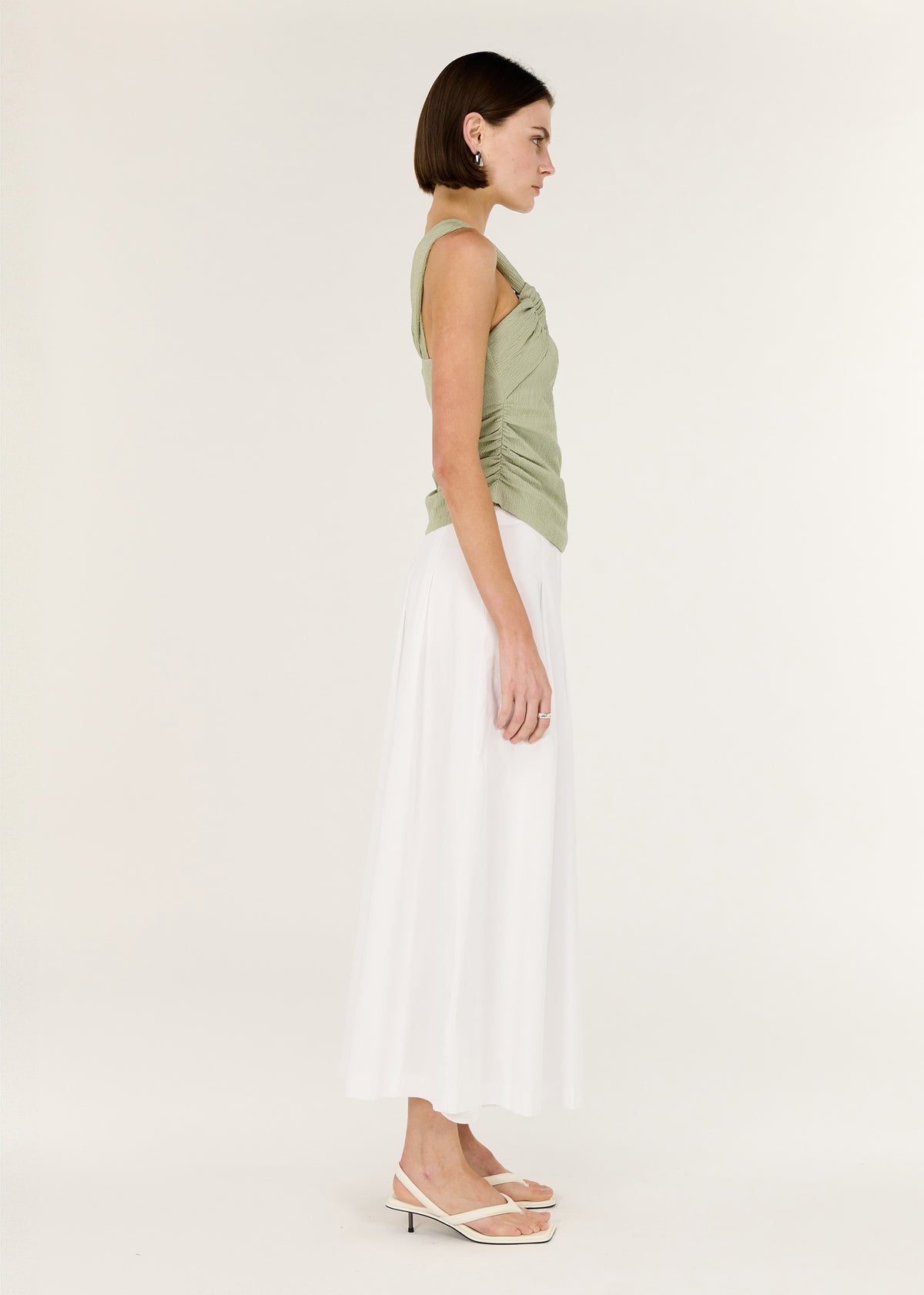 Side view of the Sage One Shoulder Knotted Top, showing a one-shoulder asymmetrical design and a soft twist detail at neckline.