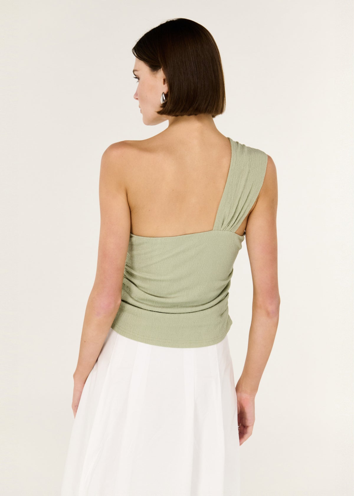 Back view of the Sage One Shoulder Knotted Top, showing a one-shoulder asymmetrical design and a soft twist detail at neckline.