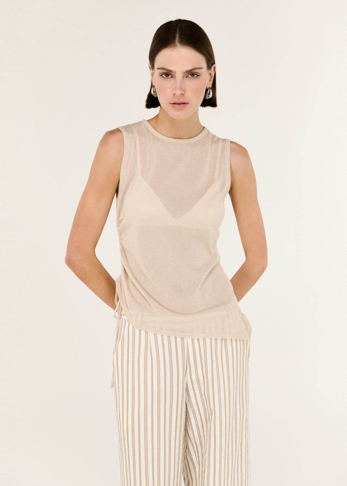 Close-up of the Sheer Drawstring Knit Tank Top, showing a sleeveless cut and an adjustable side drawstring detail.