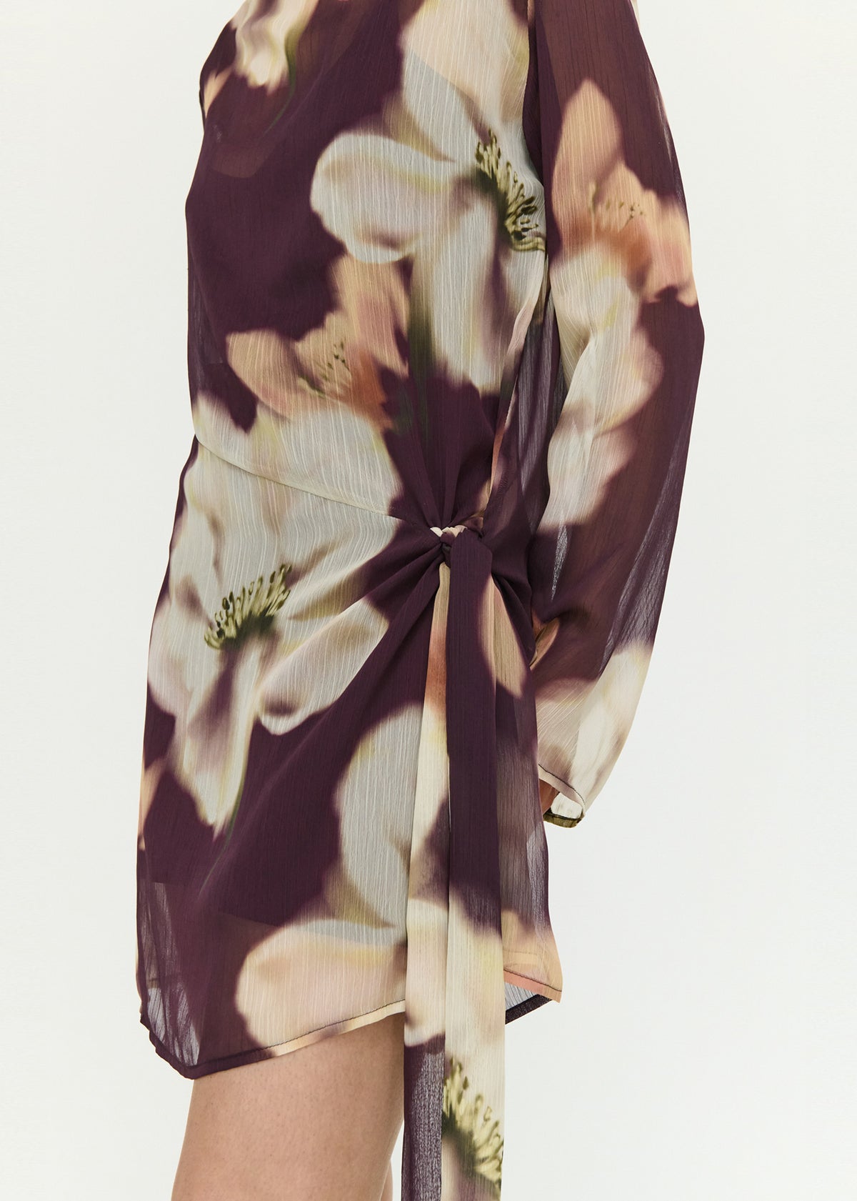 Close-up detail of the Sheer Floral Mini Dress with Tie Detail, showing knotted hem tie.