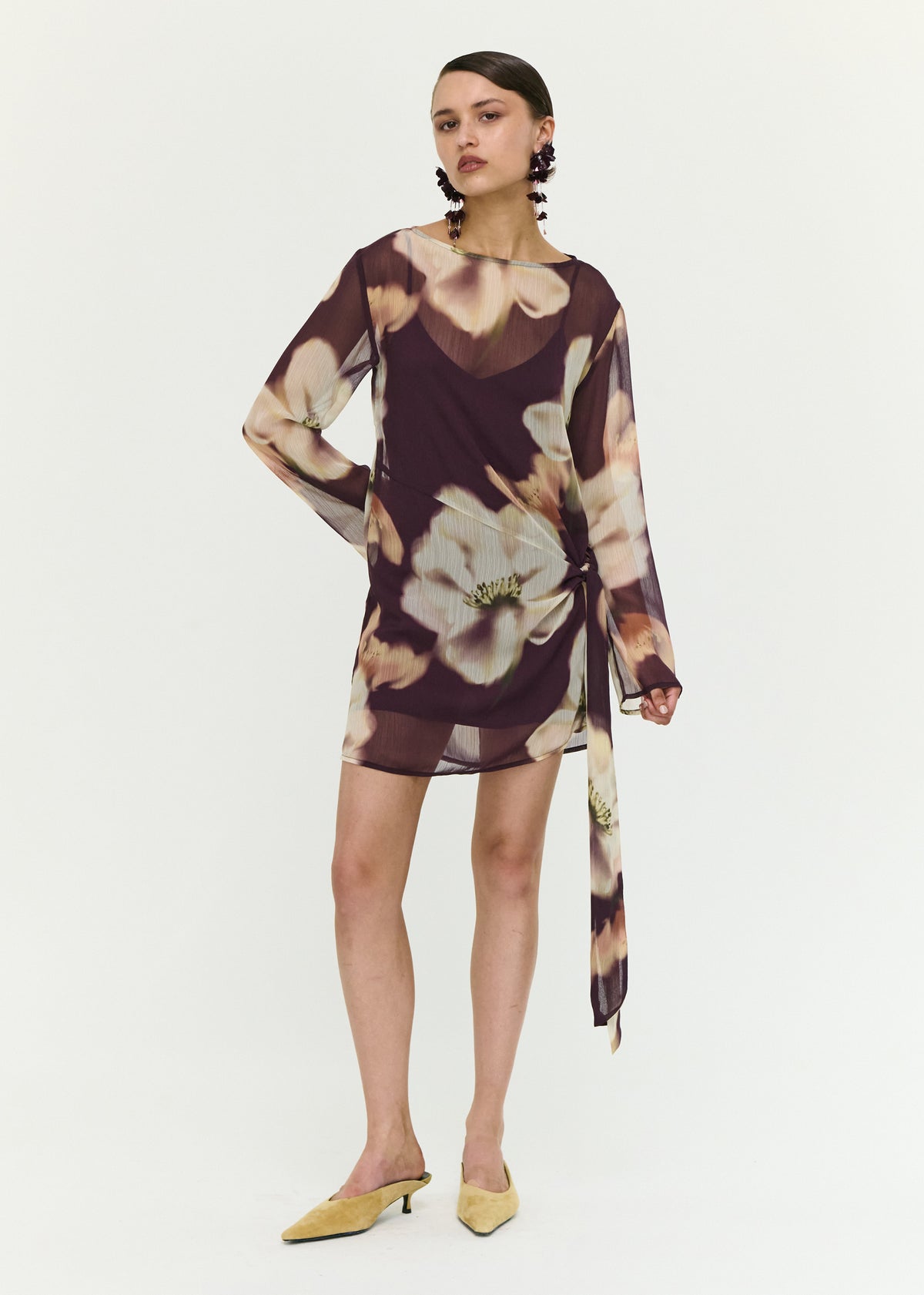 Model wearing Sheer Floral Mini Dress with Tie Detail, showing a polyester fabrication.