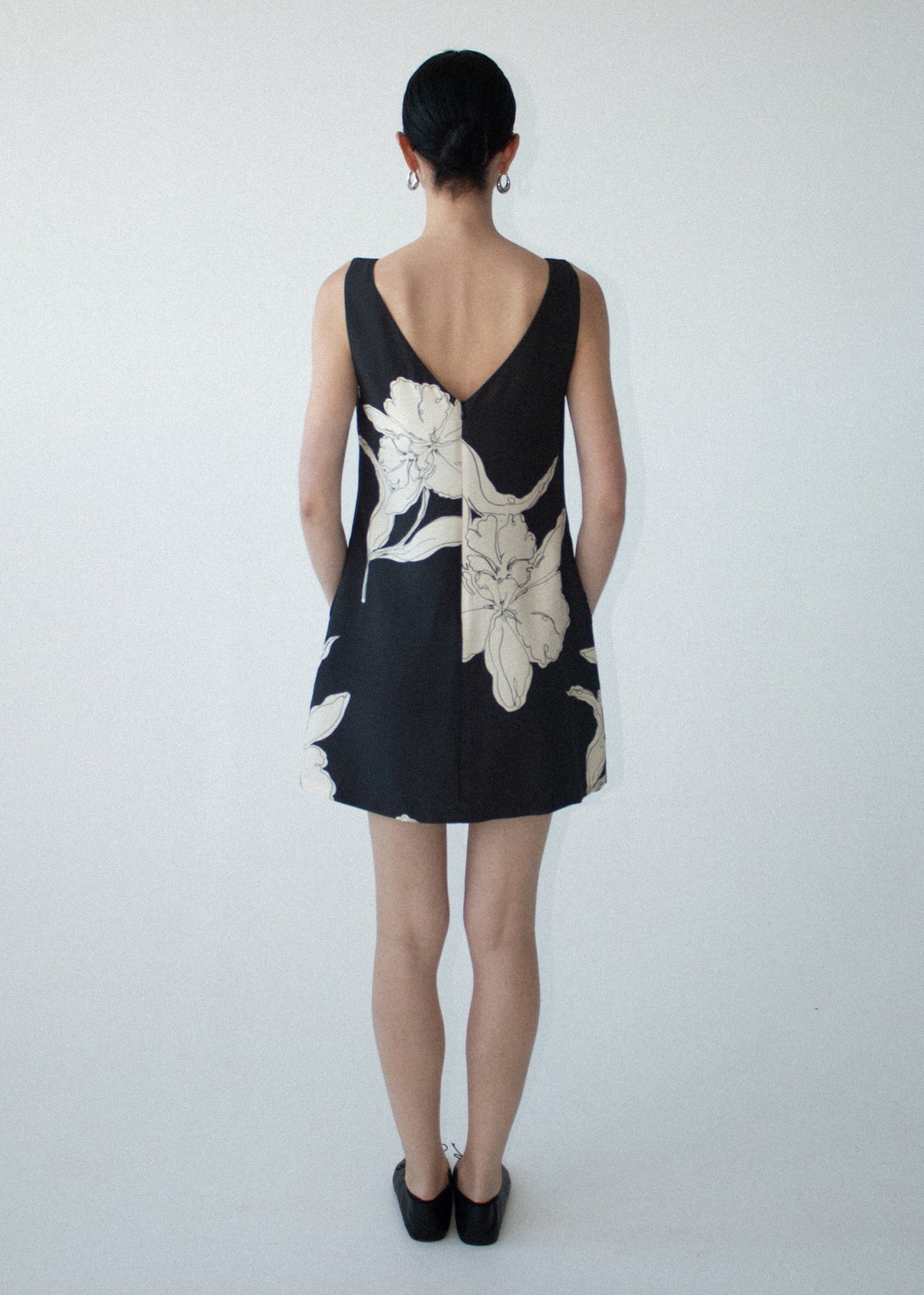 Back view of the Sketched Floral Sleeveless Mini Dress with a concealed button front closure and a lightweight woven fabrication.
