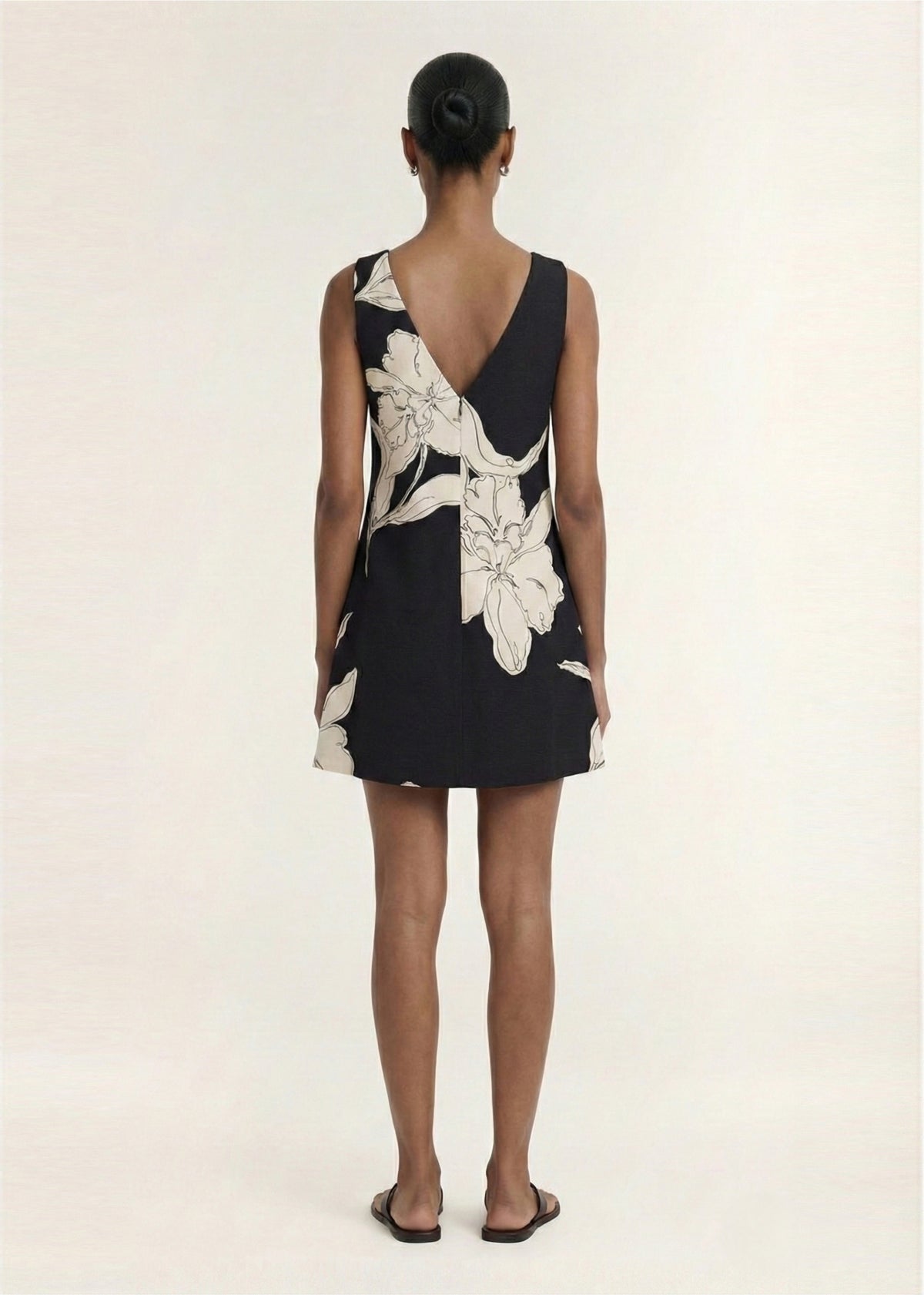 Back view of the Sketched Floral Sleeveless Mini Dress, showing a concealed button front closure and a lightweight woven fabrication.