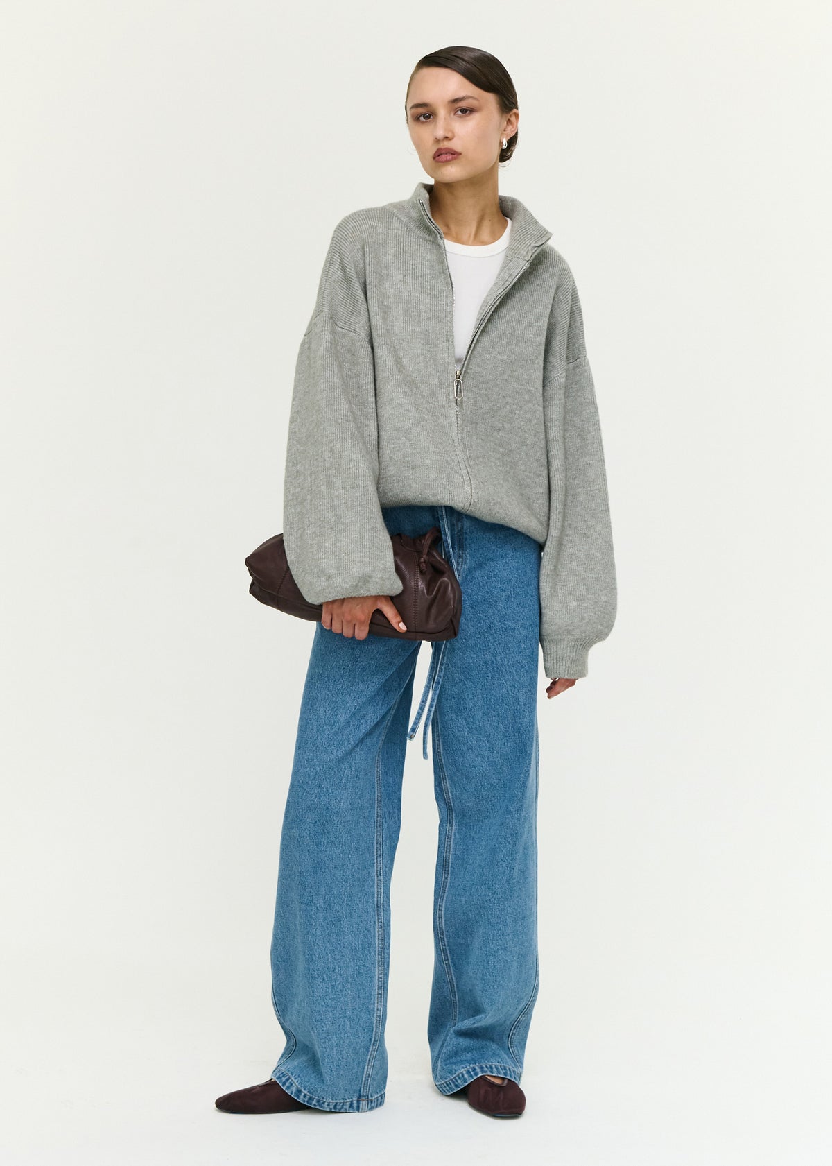 Model wearing Soft Grey Oversized Zip Cardigan with a soft ribbed knit fabrication and an oversized fit.