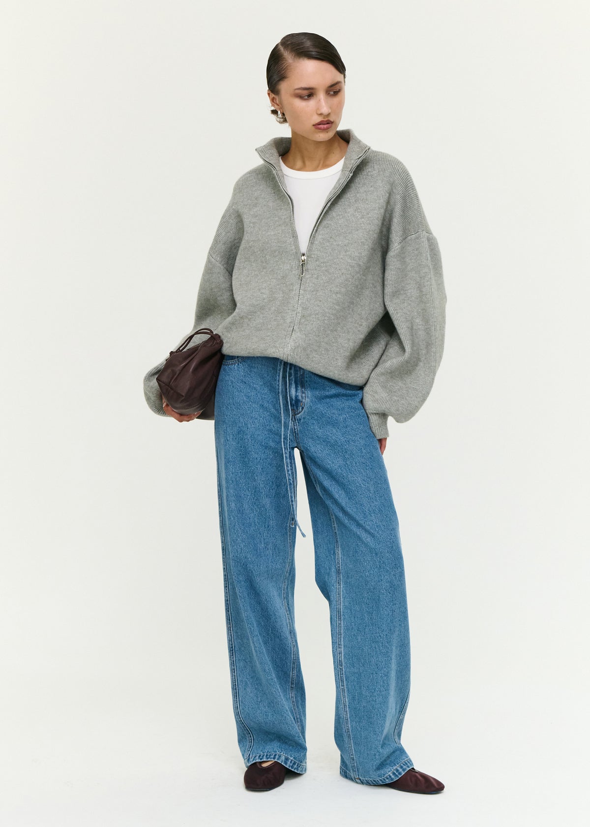 Model wearing Soft Grey Oversized Zip Cardigan with a high neckline and a front zip closure, turned to the side.