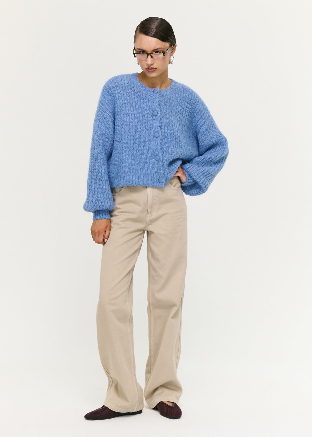 Model wearing Soft Handle Balloon Sleeve Cardigan in Blue with a button-through front and a round neckline, turned to the side.