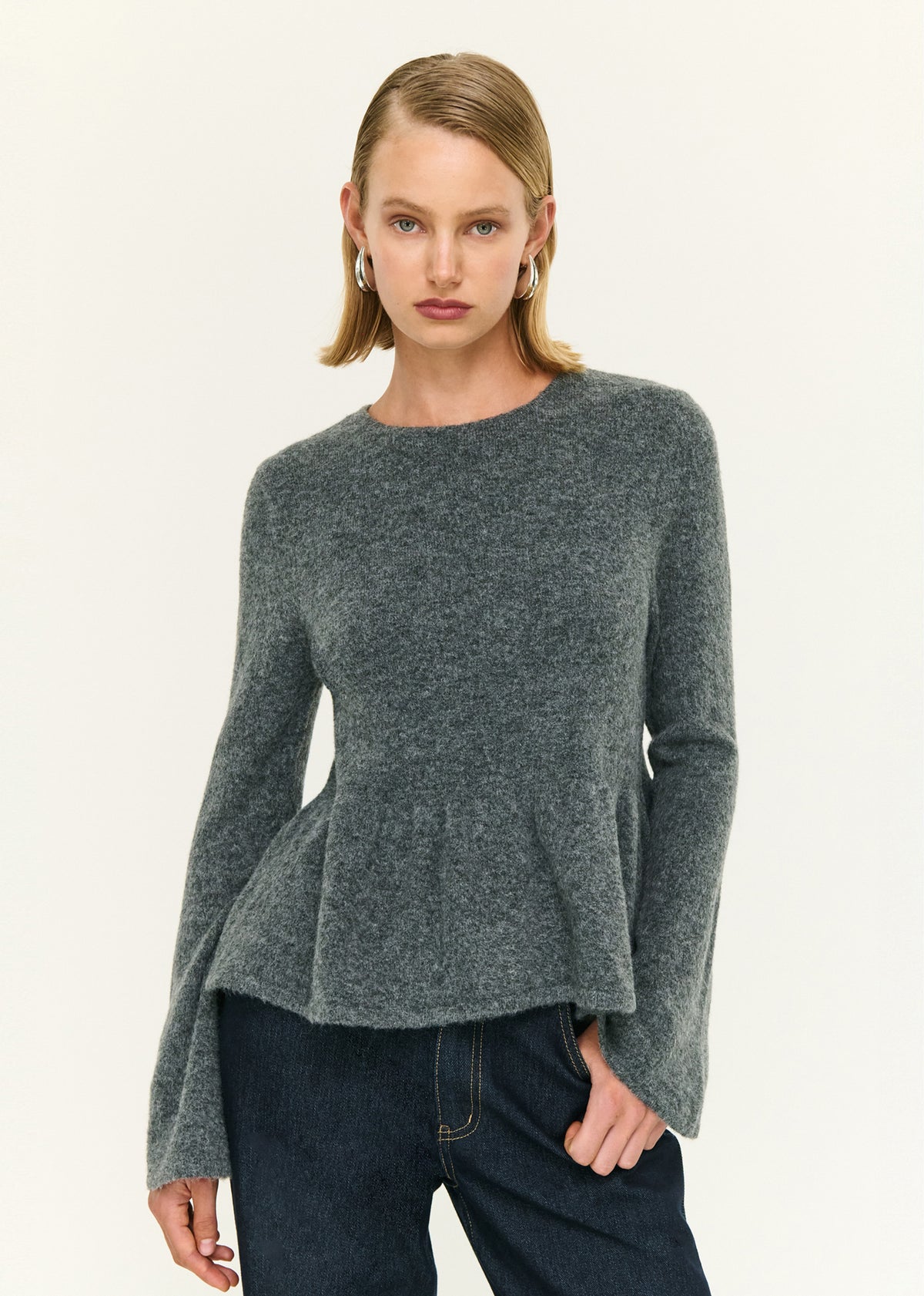 Close-up of the Soft Knit Peplum Top with Flute Sleeve, showing a crew neckline and long flared sleeves.