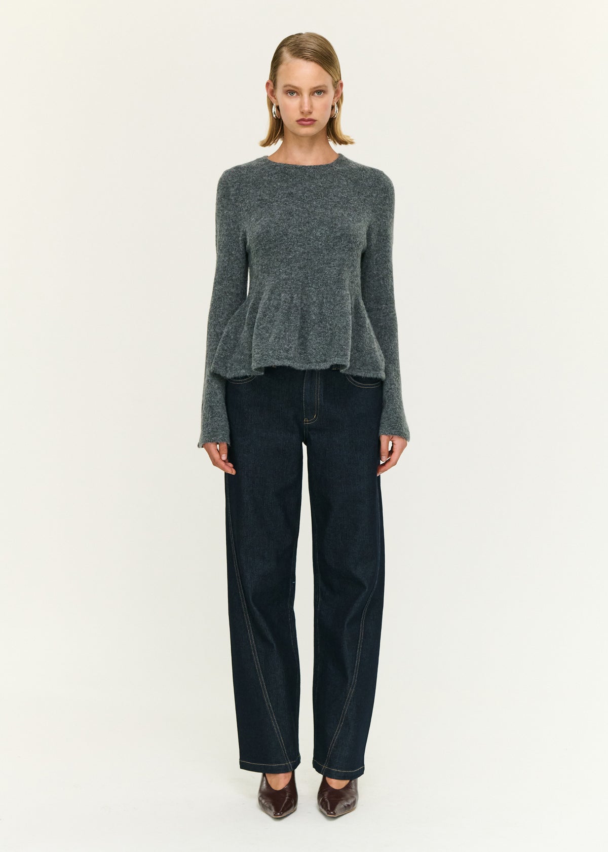 Model wearing Soft Knit Peplum Top with Flute Sleeve with a crew neckline and a peplum hem detail.