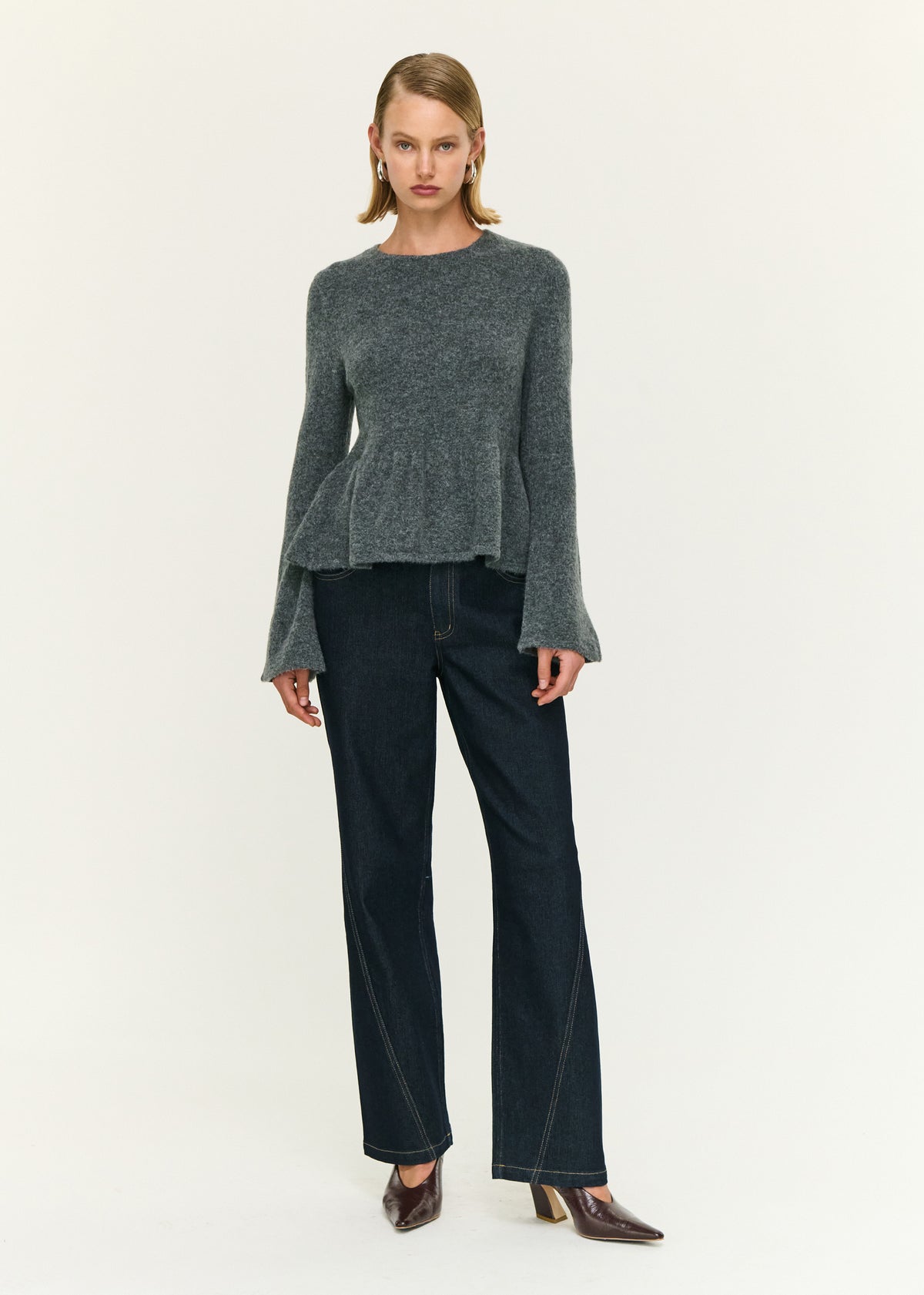 Model wearing Soft Knit Peplum Top with Flute Sleeve, showing long flared sleeves and a soft textured finish.