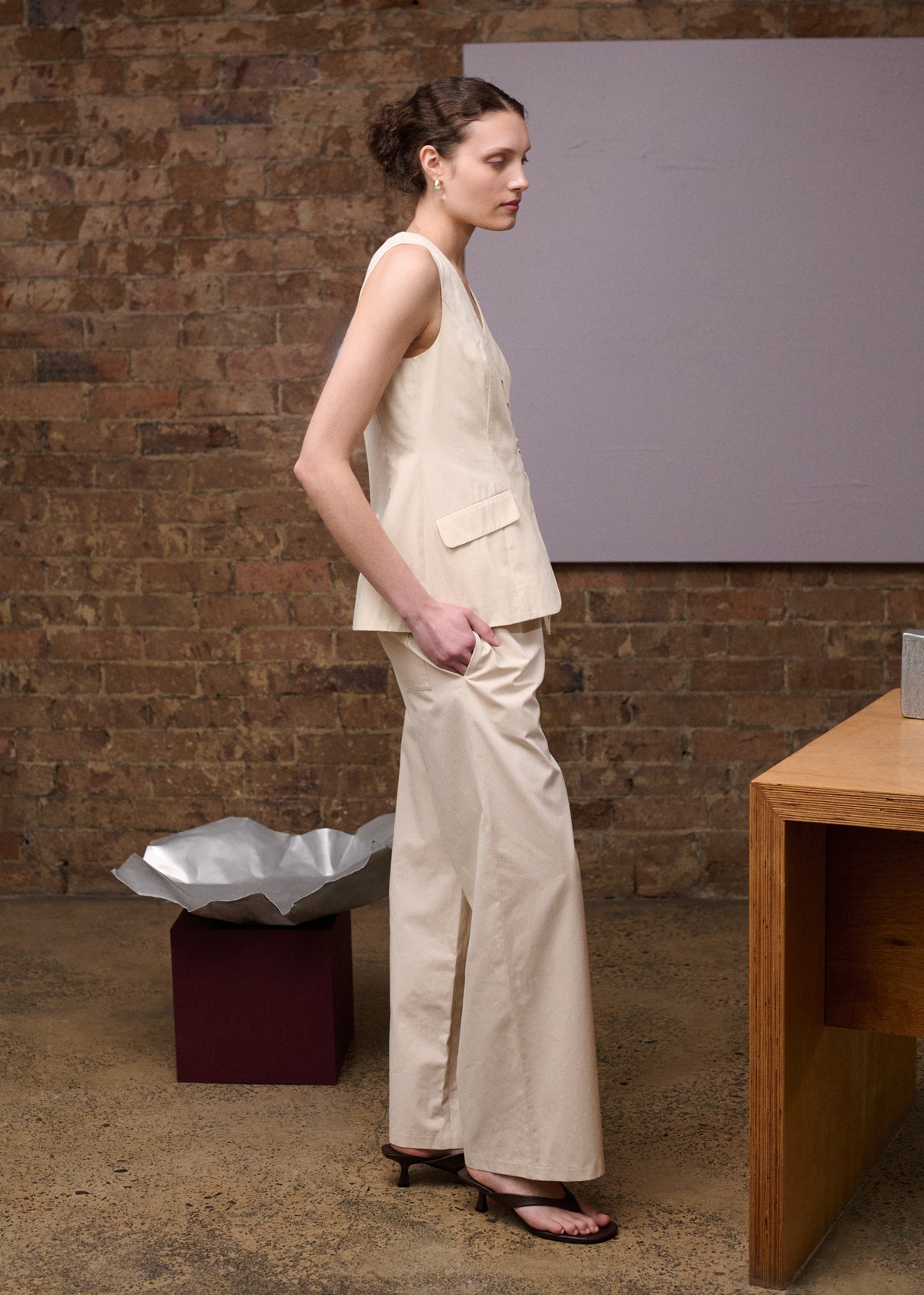 Model wearing Stone Cotton Wrap Front Vest, showing a scalloped loop-and-tie fastening and flap pockets.
