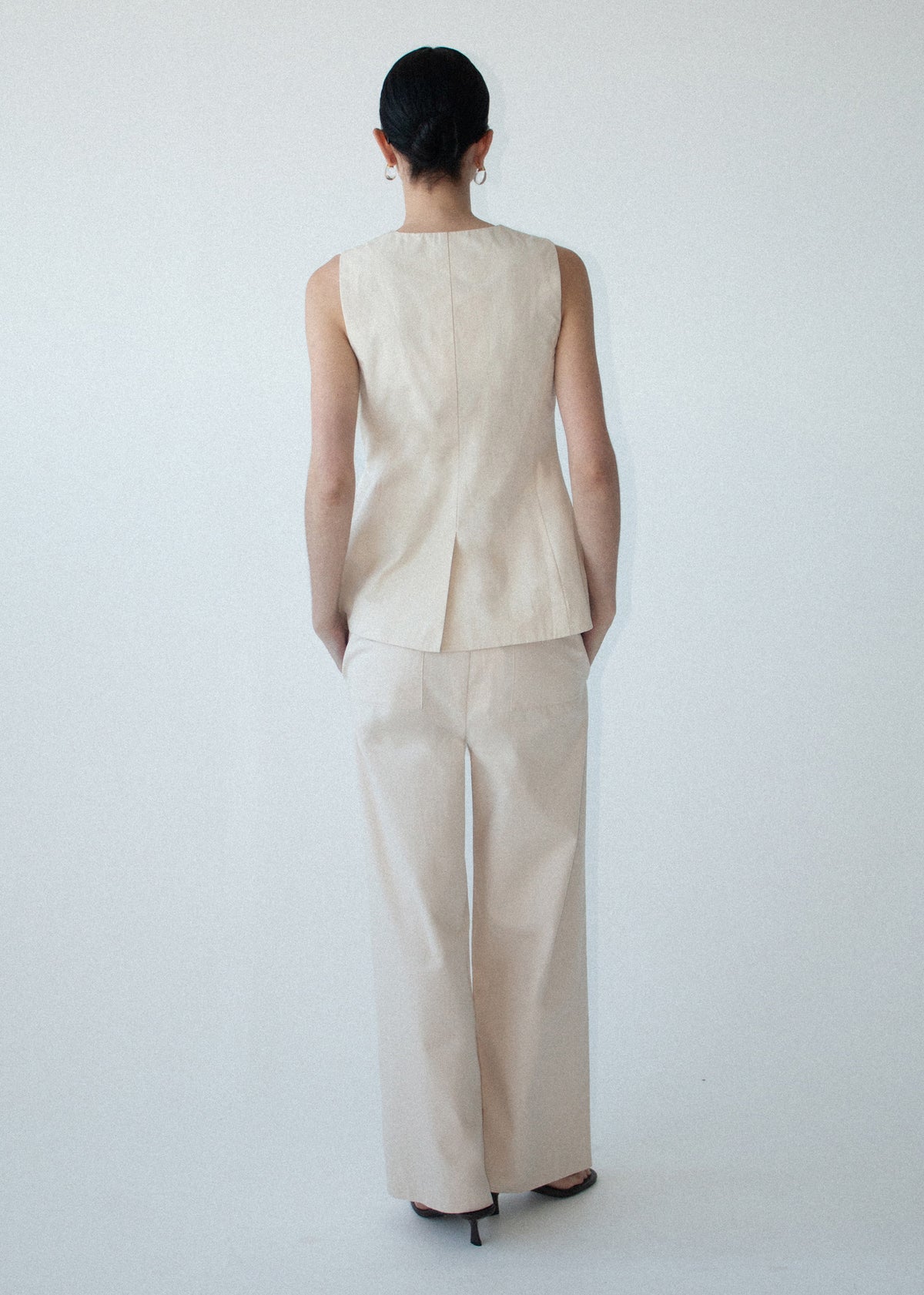 Back view of the Stone Cotton Wrap Front Vest with a scalloped loop-and-tie fastening and a lightweight structured fabrication.