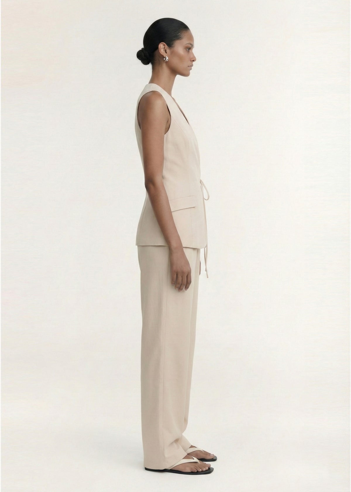 Side view of the Stone Cotton Wrap Front Vest, showing a sleeveless silhouette and a longline length.