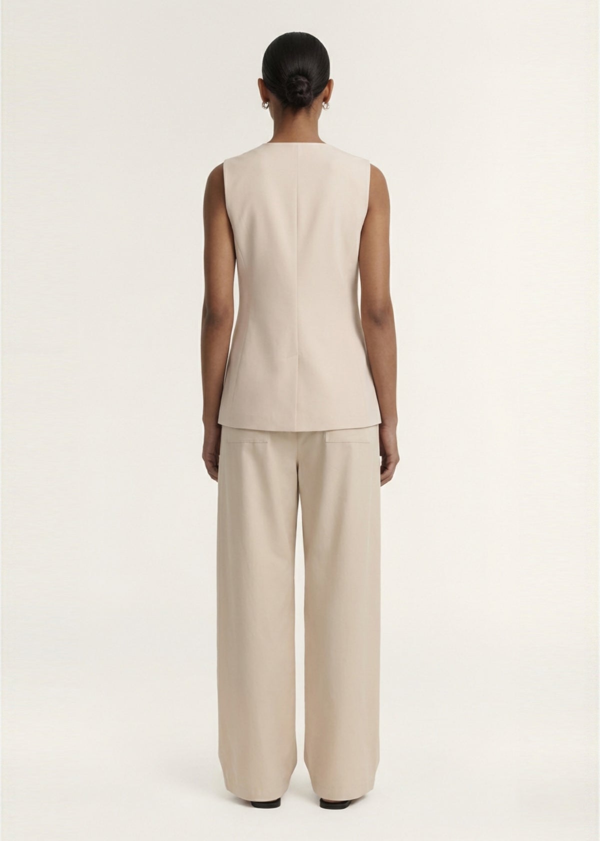 Back view of the Stone Cotton Wrap Front Vest, showing a scalloped loop-and-tie fastening and a lightweight structured fabrication.