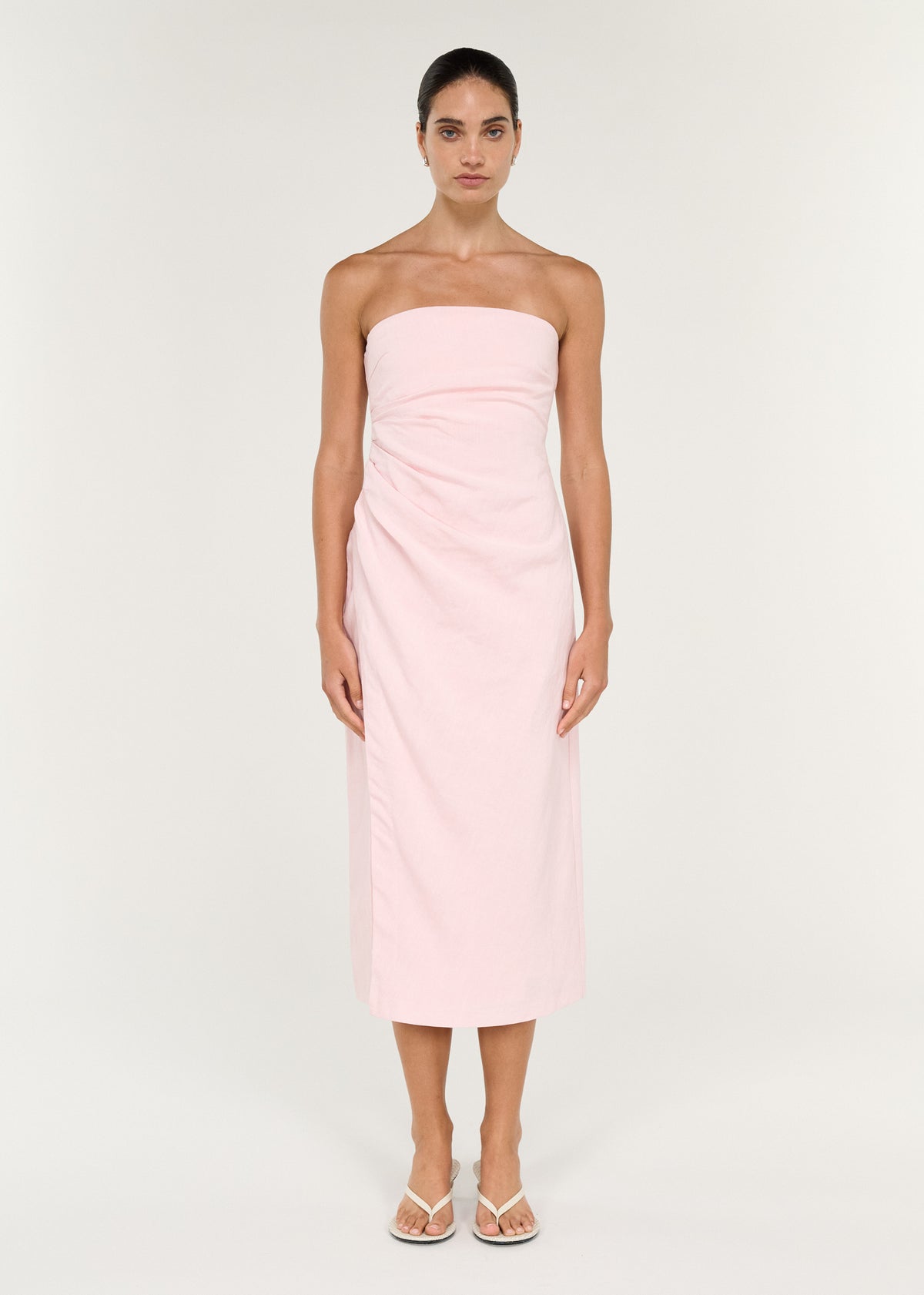 Model wearing Strapless Wrap Midi Dress in Soft Pink with a lightweight woven fabrication and a soft blush pink hue.