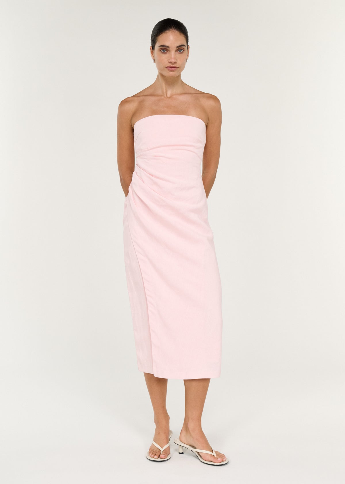 Model wearing Strapless Wrap Midi Dress in Soft Pink, showing a strapless silhouette and a straight neckline.
