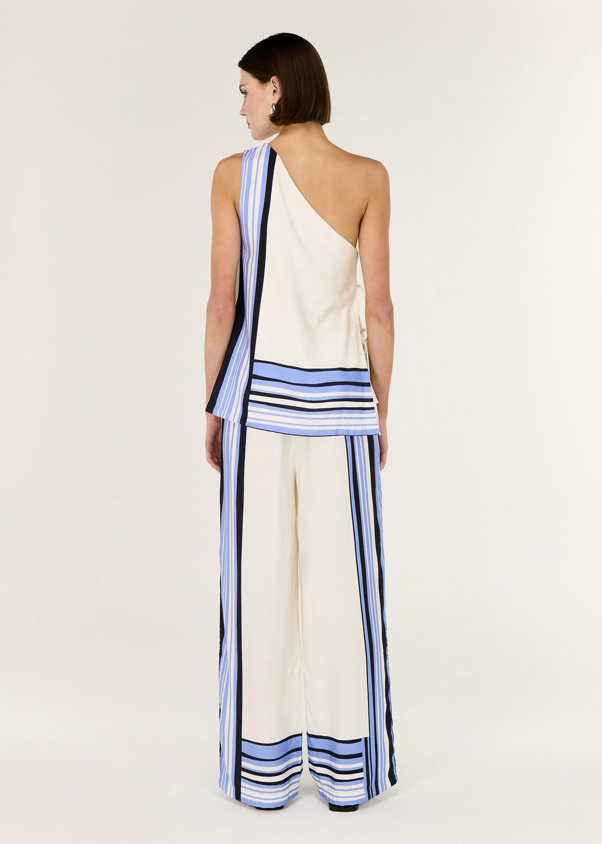 Model wearing Stripe One Shoulder Top with a spliced stripe hem detail and a fully lined, turned to the side.