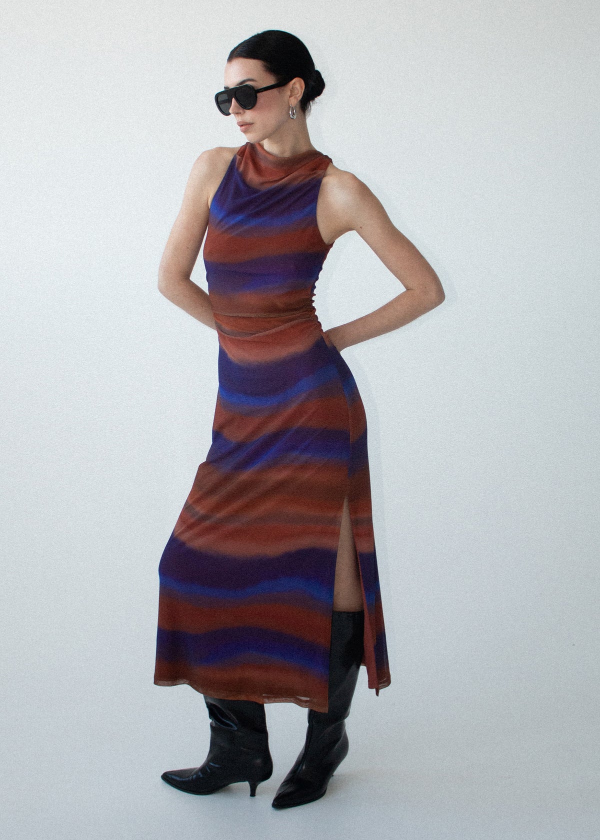Model wearing Sunset Ombre Print Sleeveless Mesh Midi Dress with a fully lined and a soft stretch mesh fabrication, turned to the side.