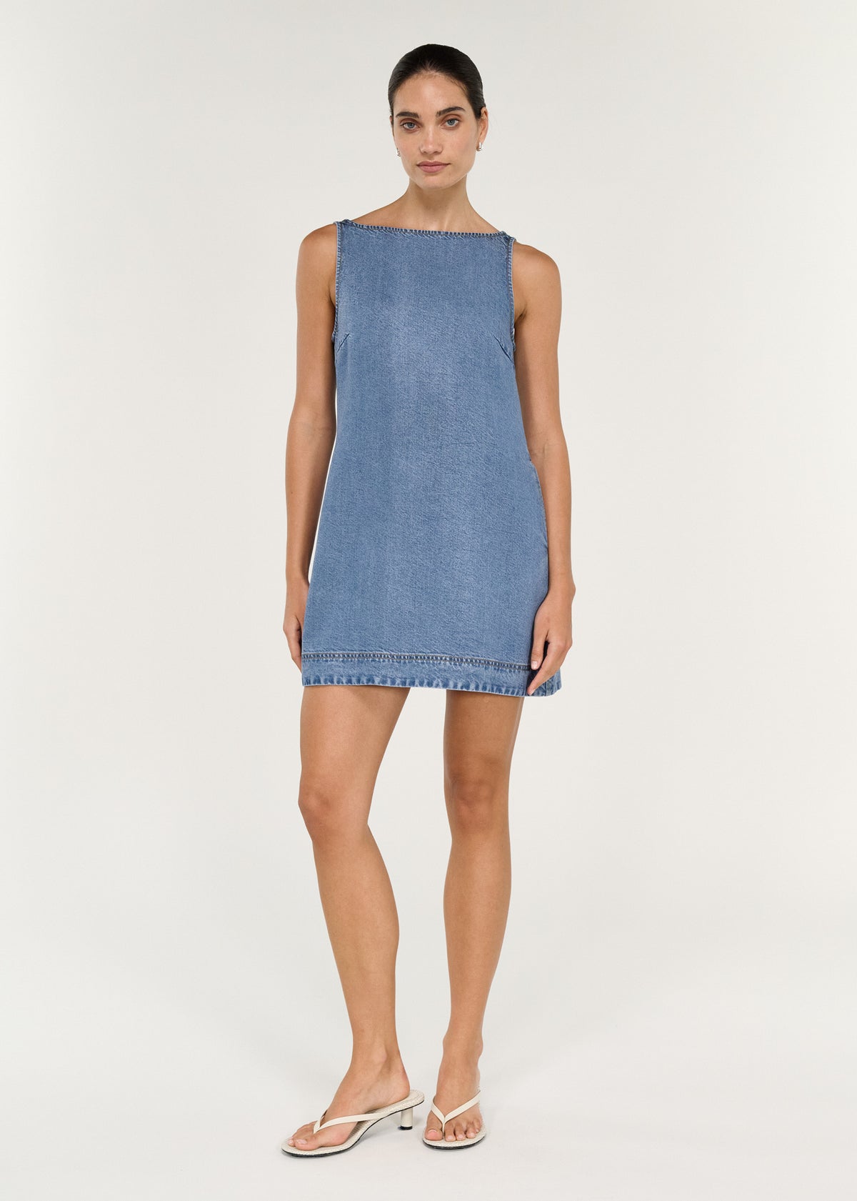 Chambray Denim Sleeveless Mini Dress on model, showcasing A-line silhouette and high boat neckline.