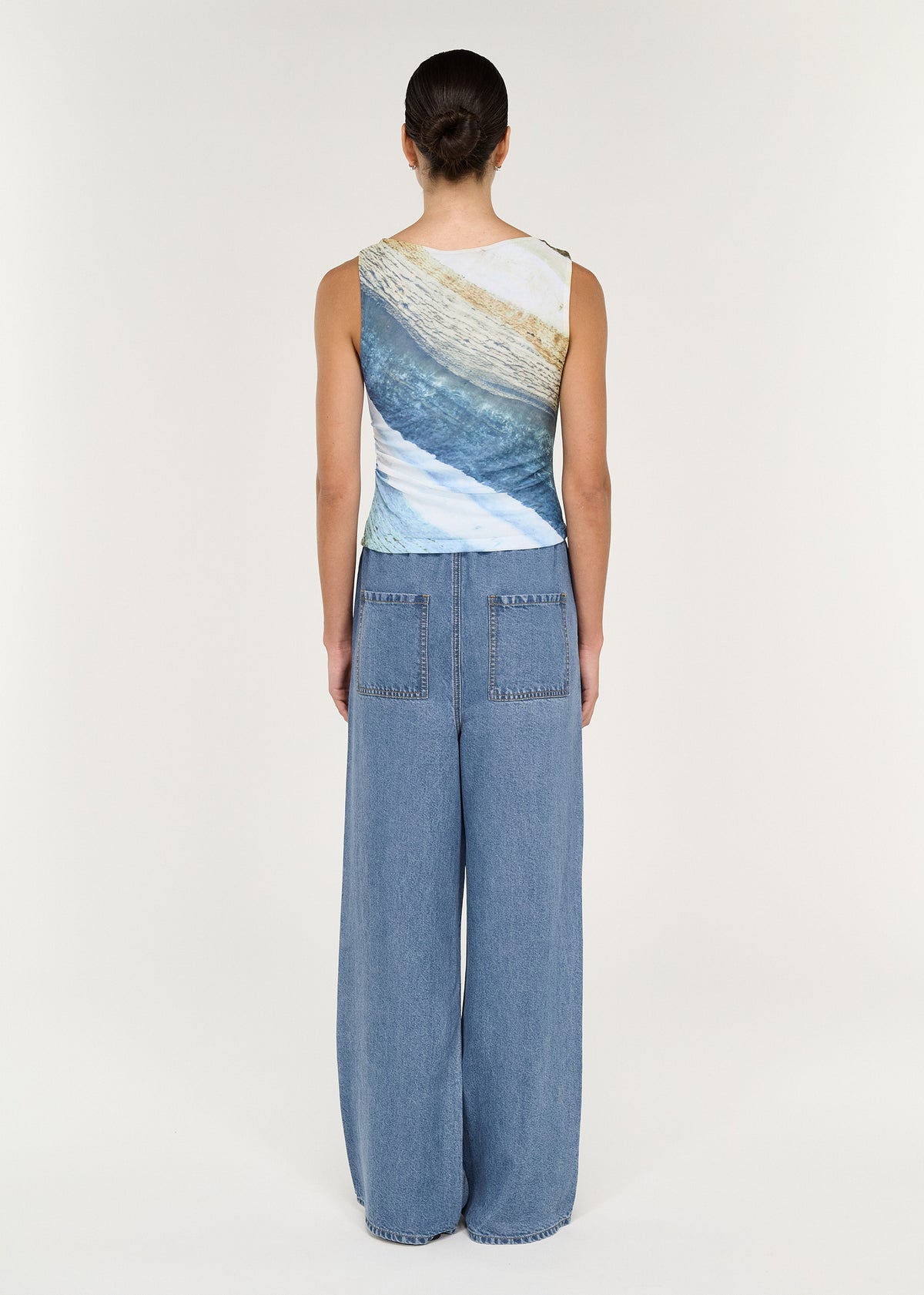 Model wearing a back view of Chambray Denim Relaxed Drawstring Pant with a stylish graphic tank top.