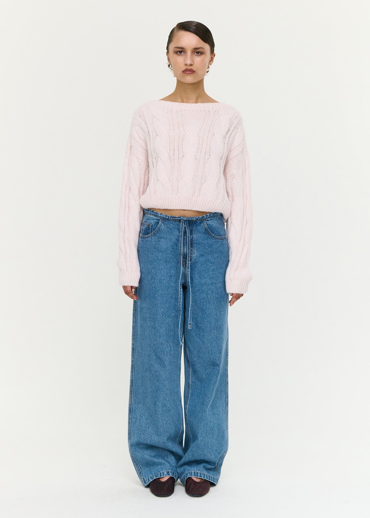 Model wearing Tie Waist Detail Mid Rise Jeans with a mid-rise waist and a rigid denim fabrication.