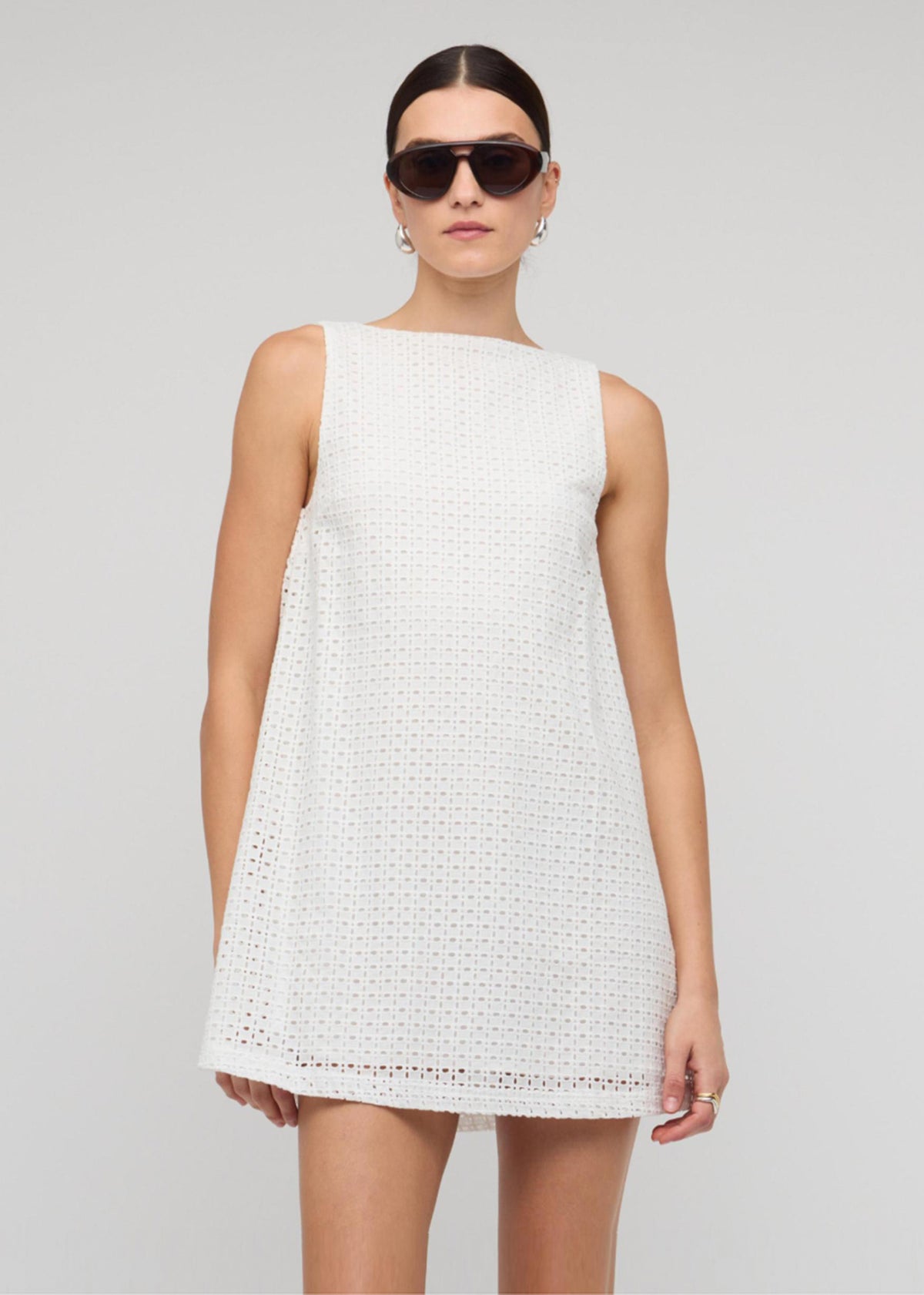 Model wearing White Broderie Mini Shift Dress with a crisp white broderie fabric and a mini shift silhouette.