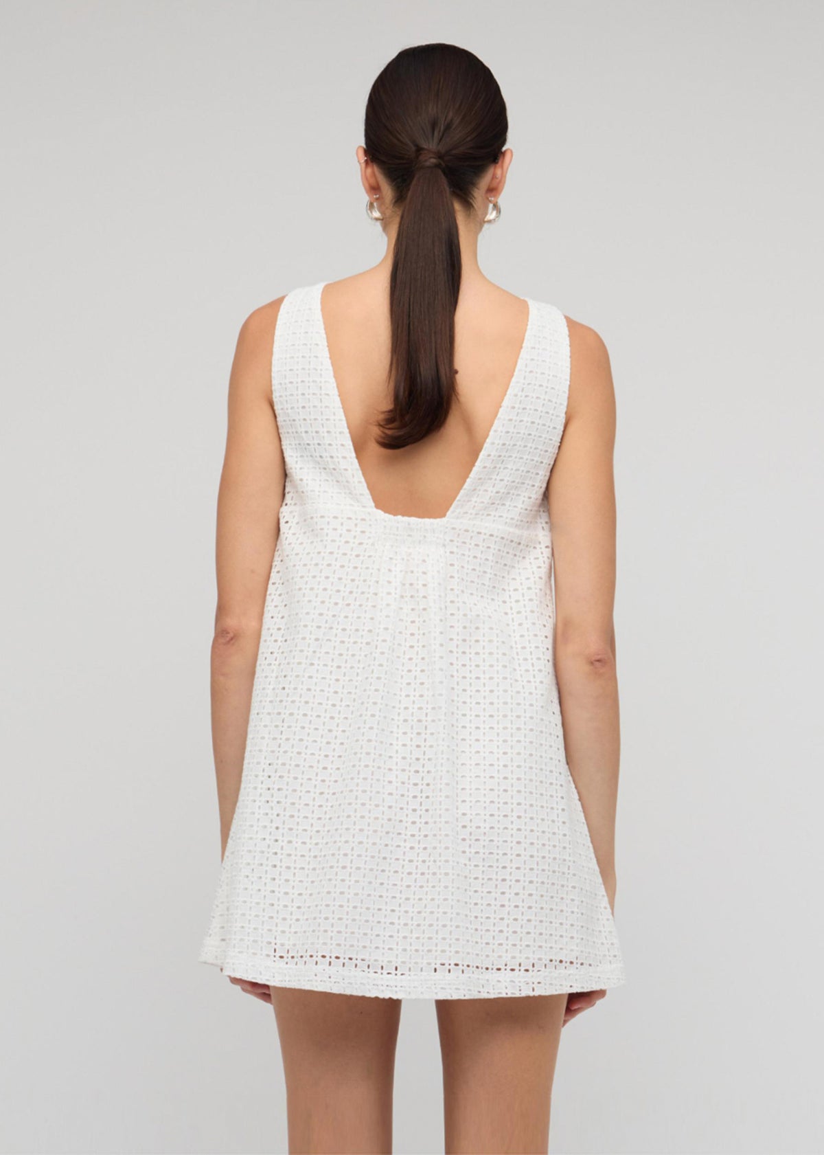 Back view of the White Broderie Mini Shift Dress with a crisp white broderie fabric and a deep V-back detail.