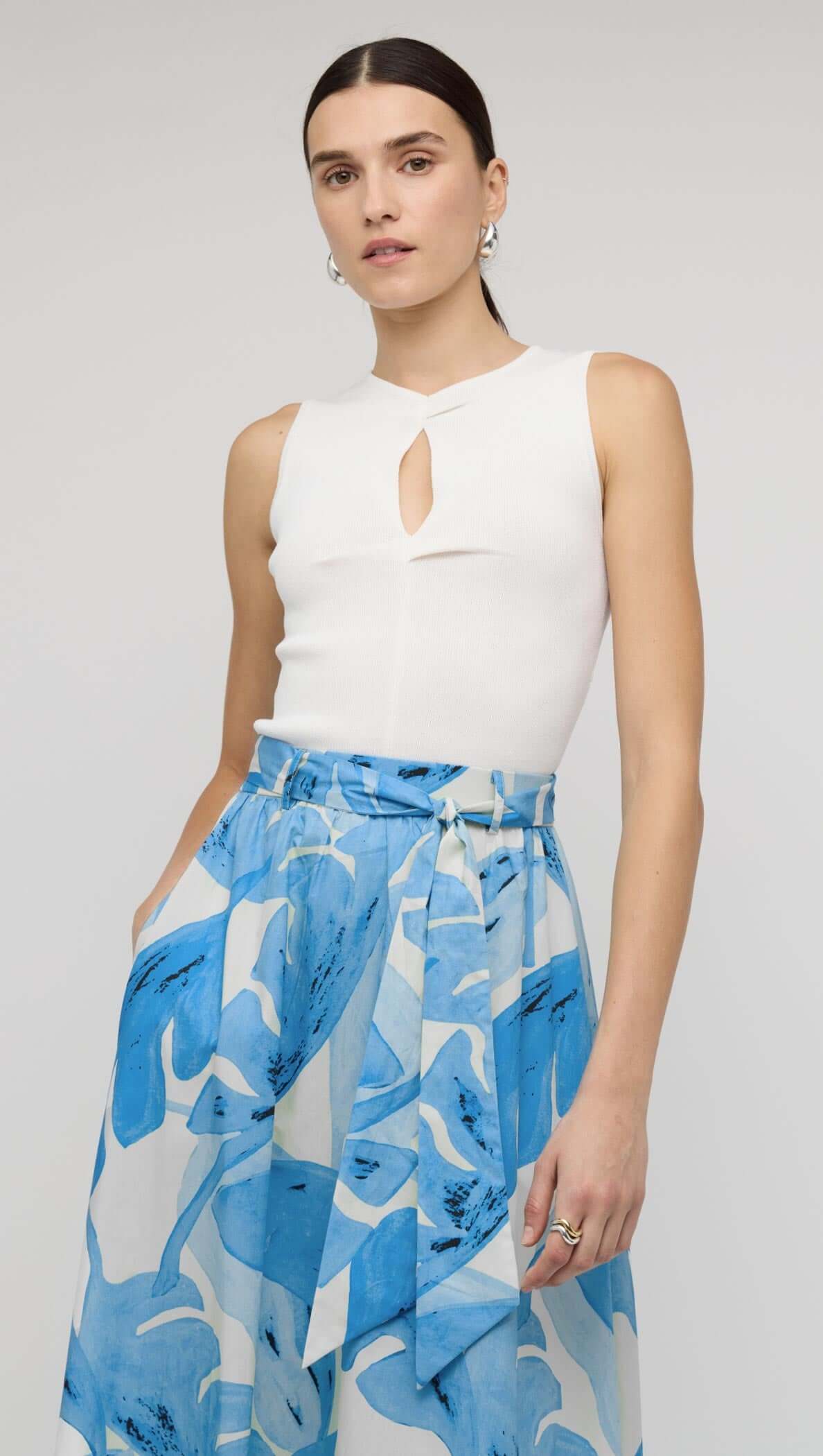 Model wearing a White Cut-Out Sleeveless Knit Top paired with a blue floral skirt.