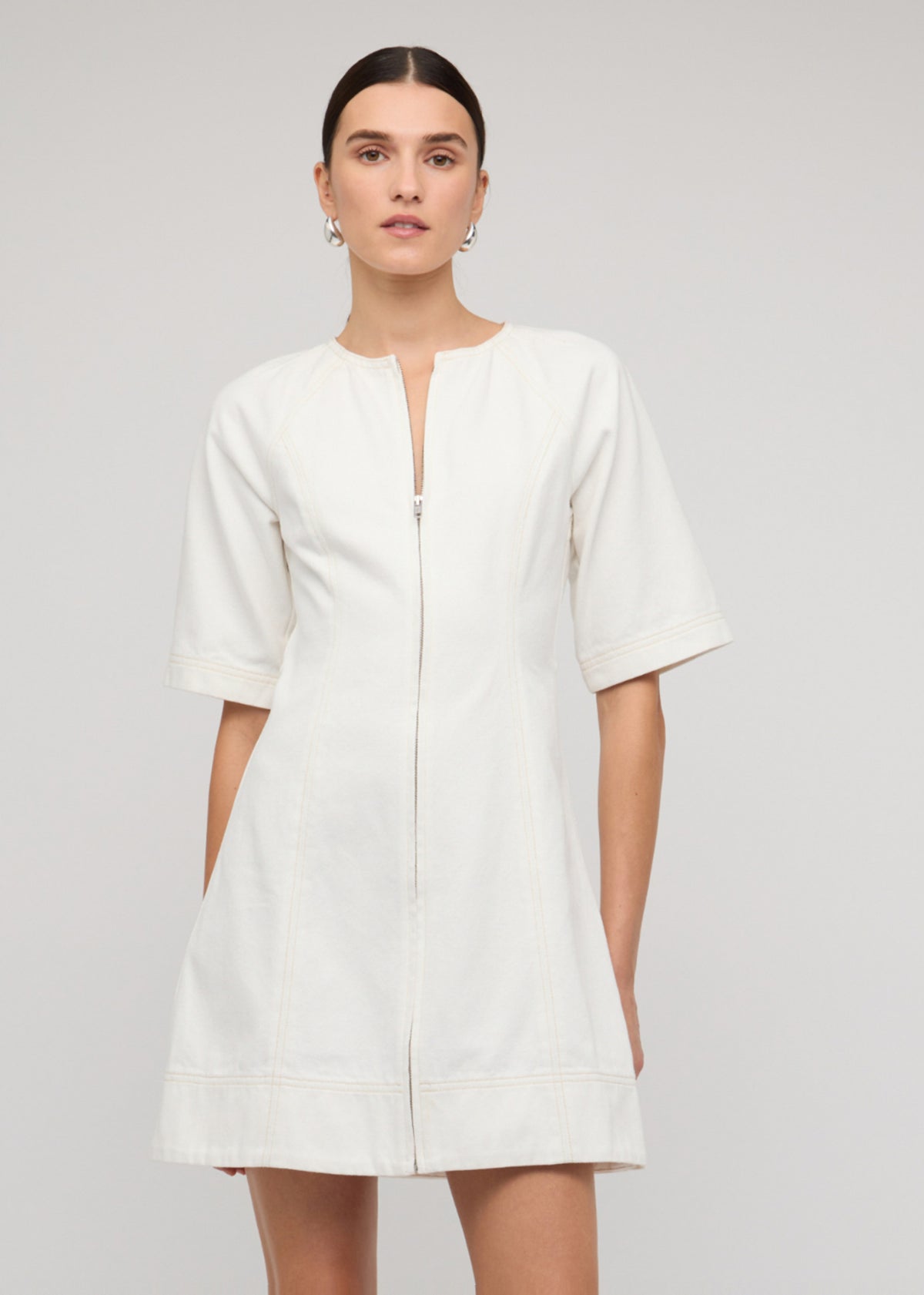 Model wearing White Denim Mini Dress With Front Zip with short sleeves and a centre-front exposed zip.