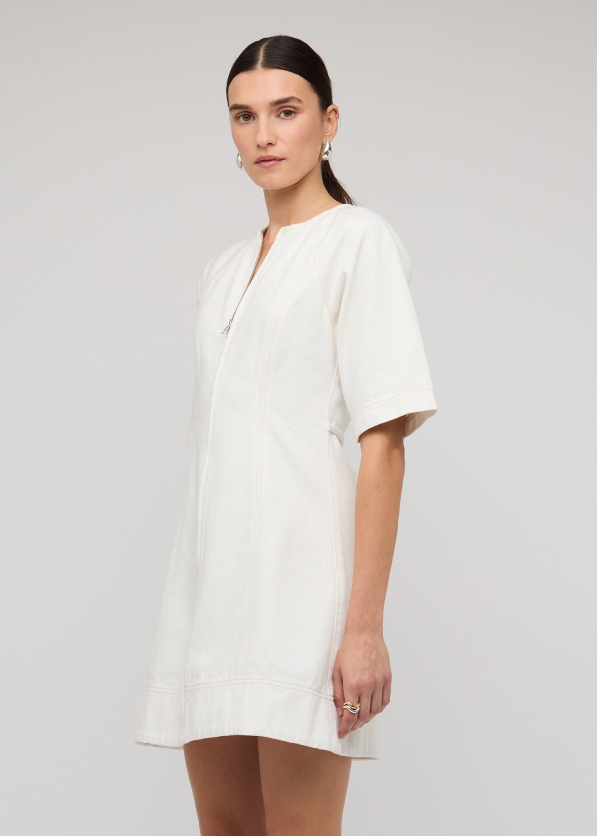 Close-up of the White Denim Mini Dress With Front Zip, showing short sleeves and a tie-back waist detail.