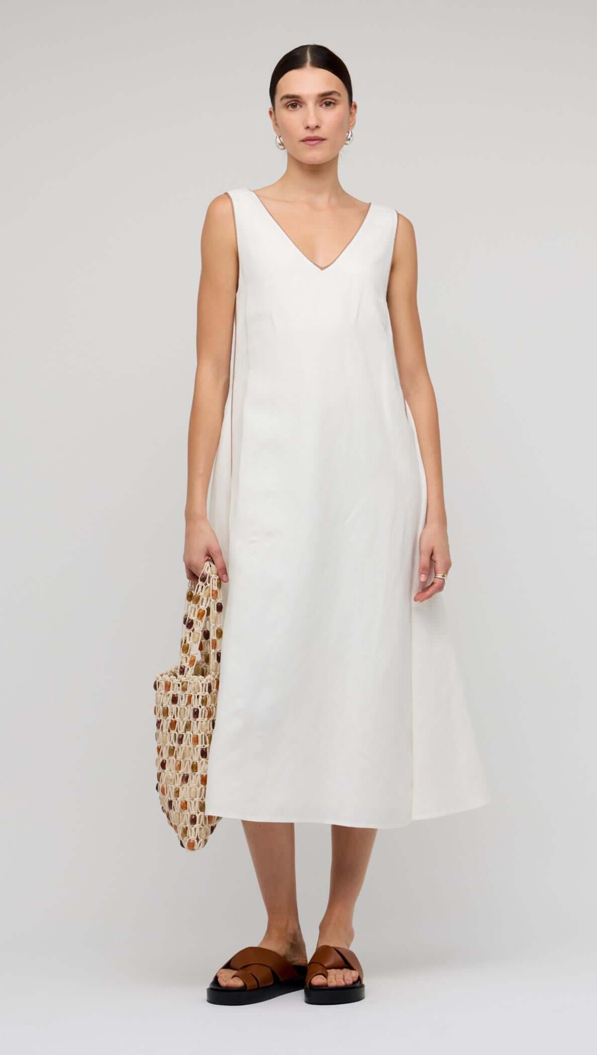 White Godet Linen Midi Dress worn by a model, featuring a V-neckline and flowy skirt.