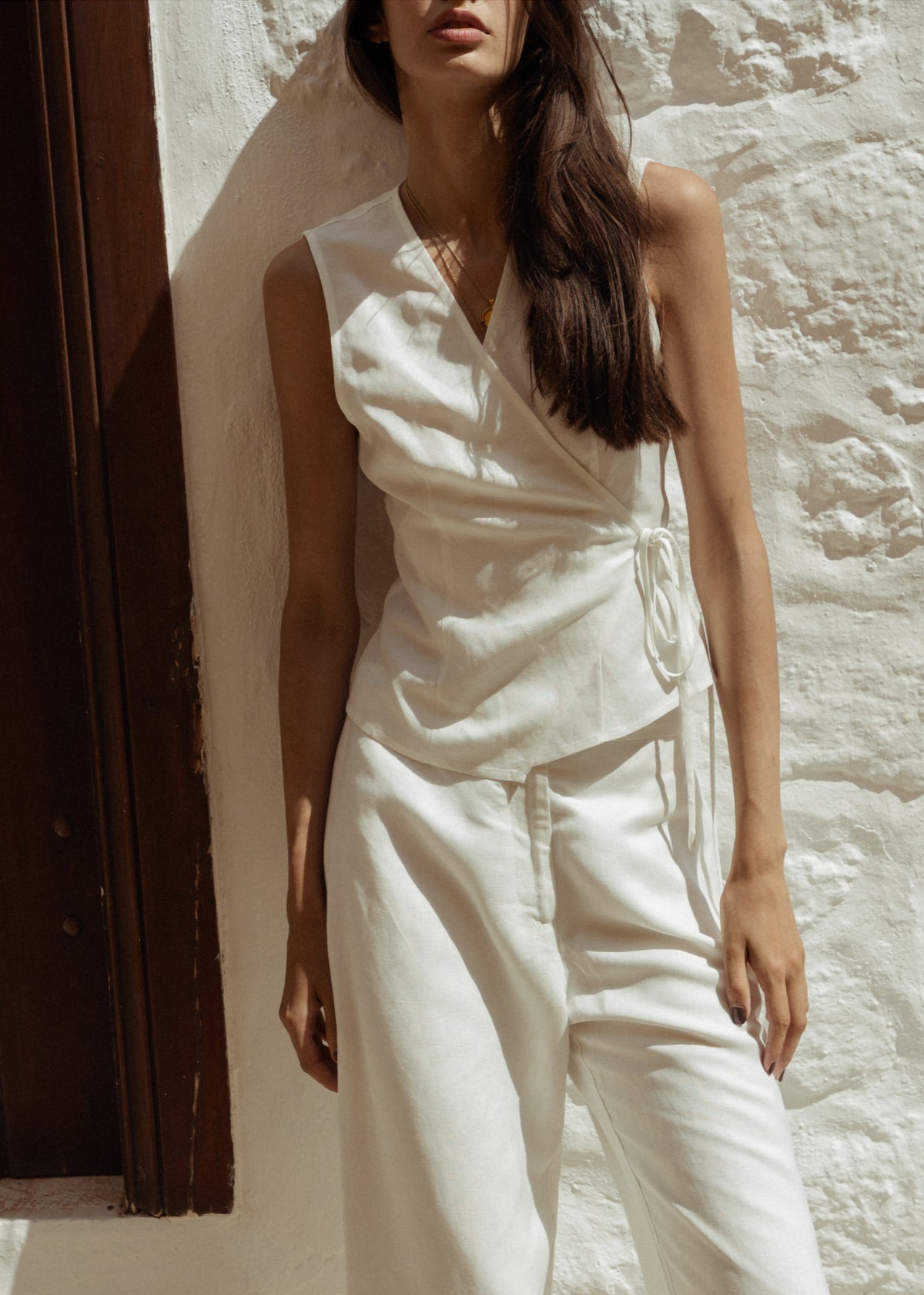 Model wearing White Linen Wide Leg Pants with a wide-leg silhouette and side pockets, turned to the side.