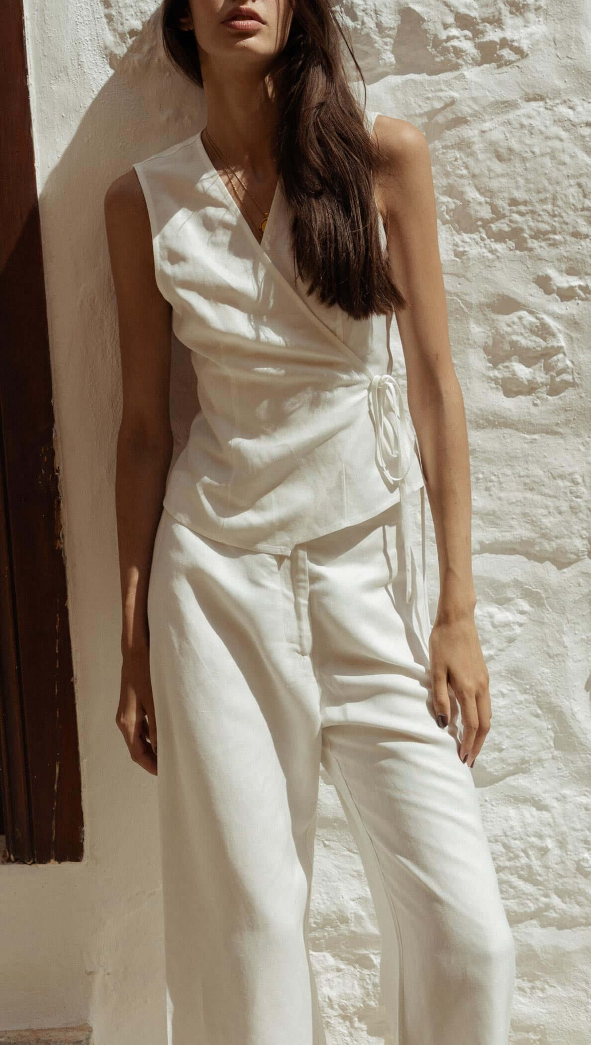 Model wearing a White Sleeveless Linen Wrap Top with a deep V-neckline and adjustable tie waist.
