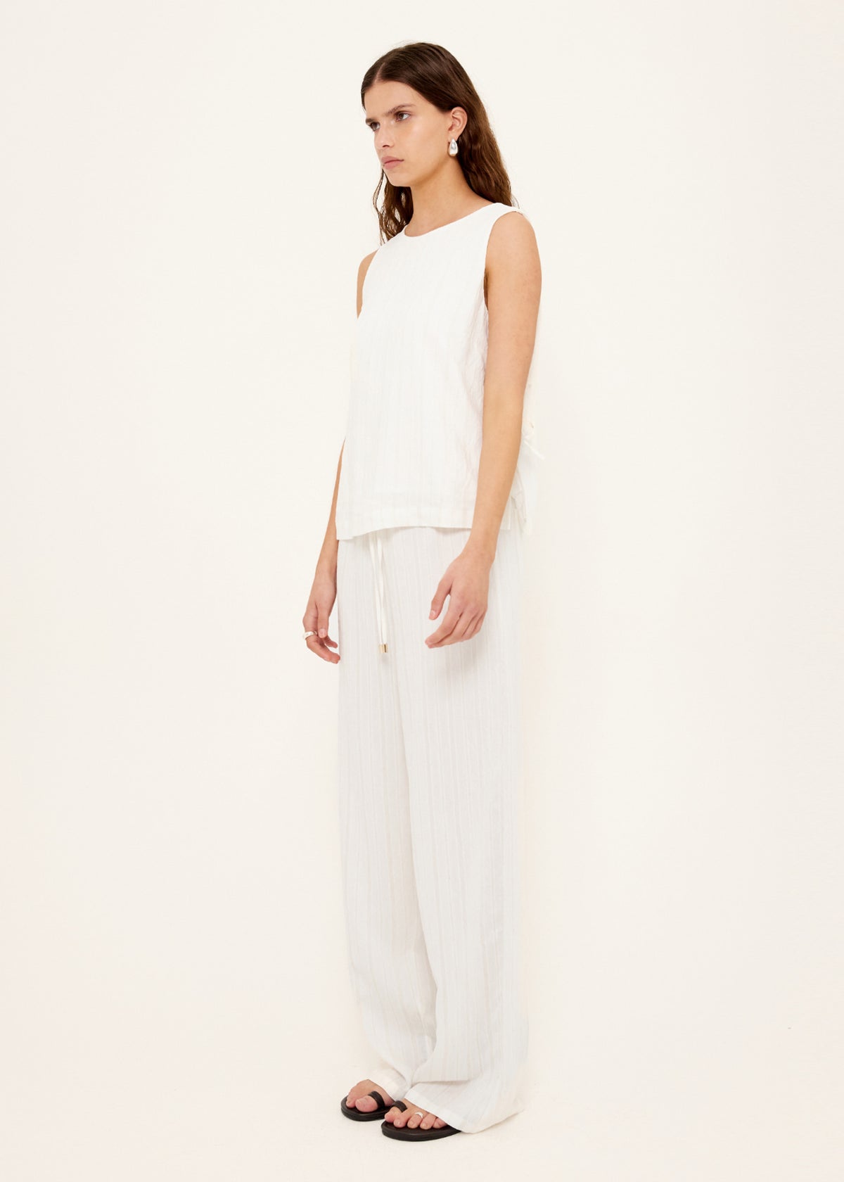 Model wearing White Wide Leg Drawstring Pants with a full length and a relaxed wide-leg silhouette, turned to the side.