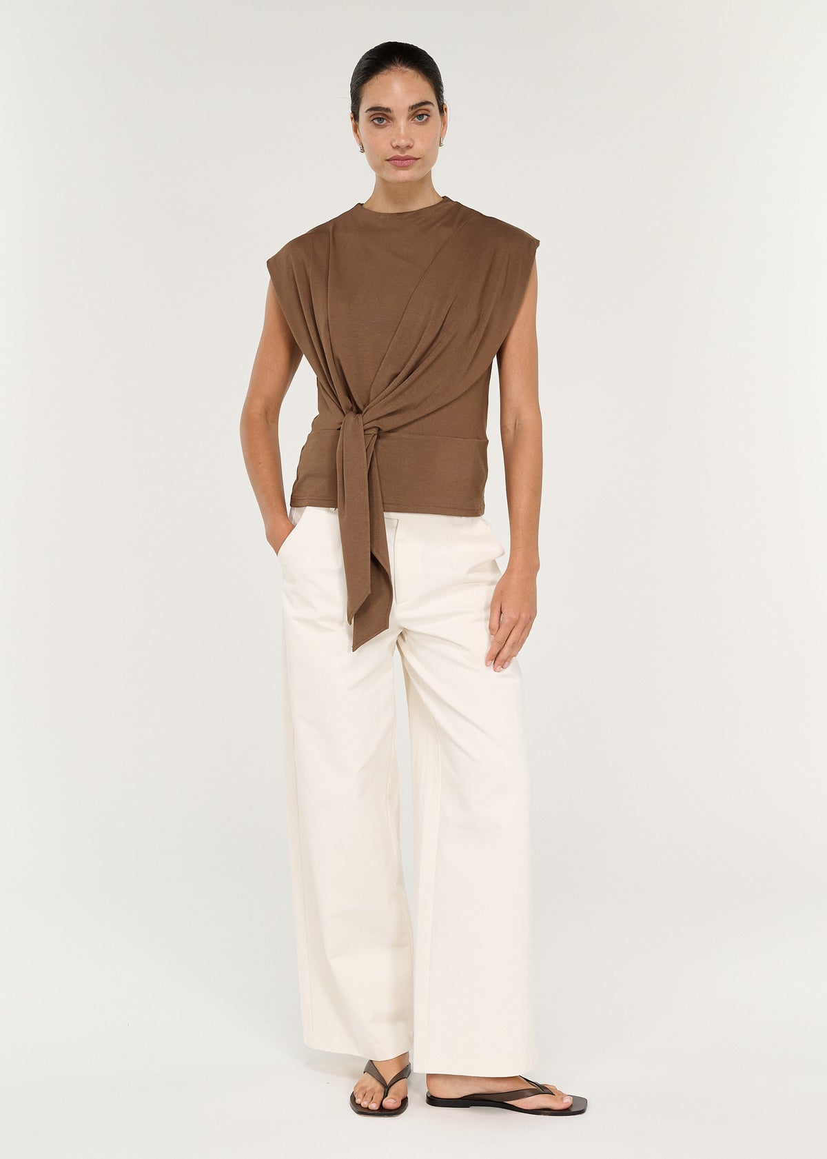 Model wearing a Draped Cotton Jersey Top in Mocha with relaxed fit and tie detail, paired with light trousers.